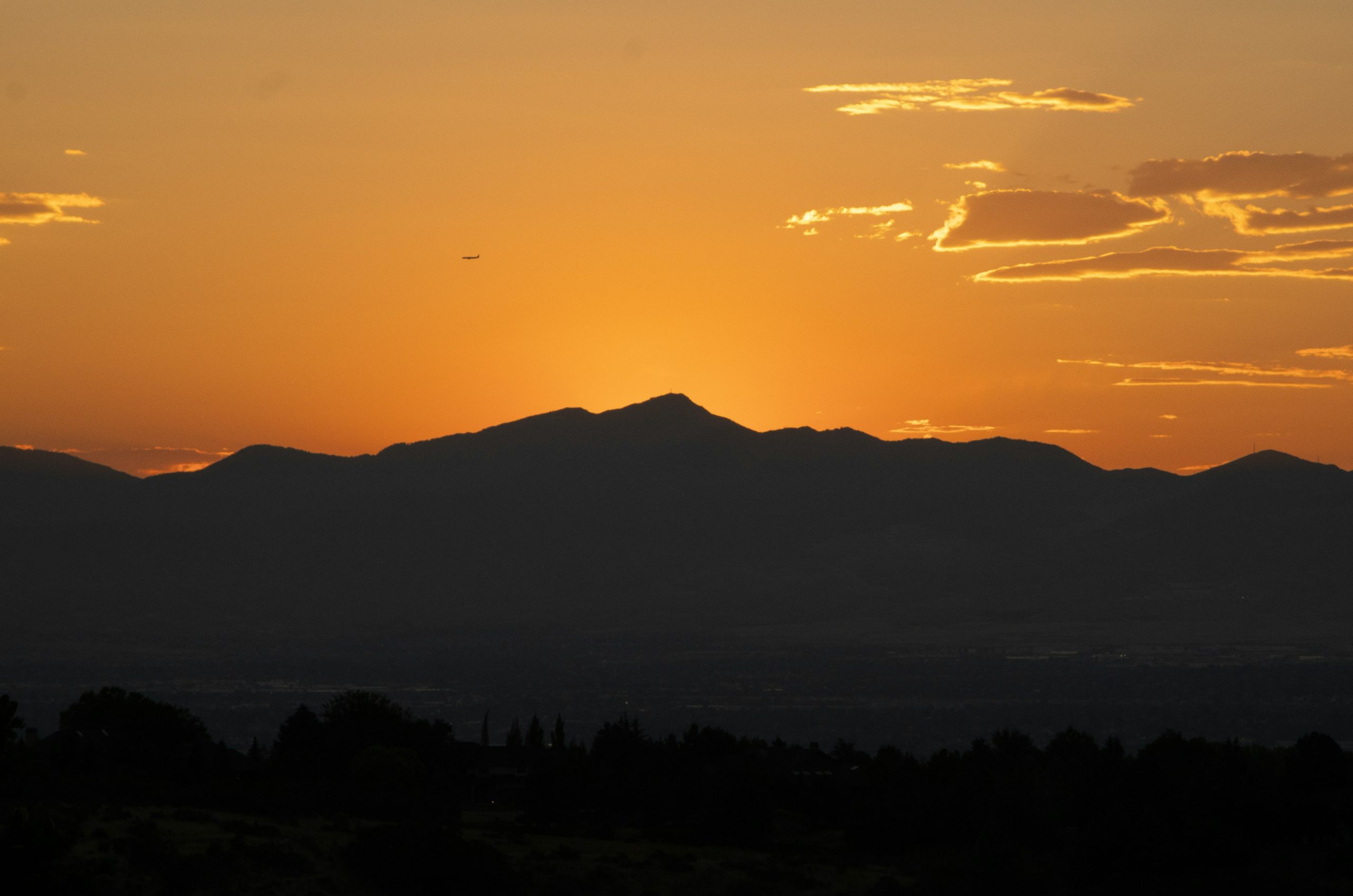 Silhouette of mountains against a vibrant orange sunset.