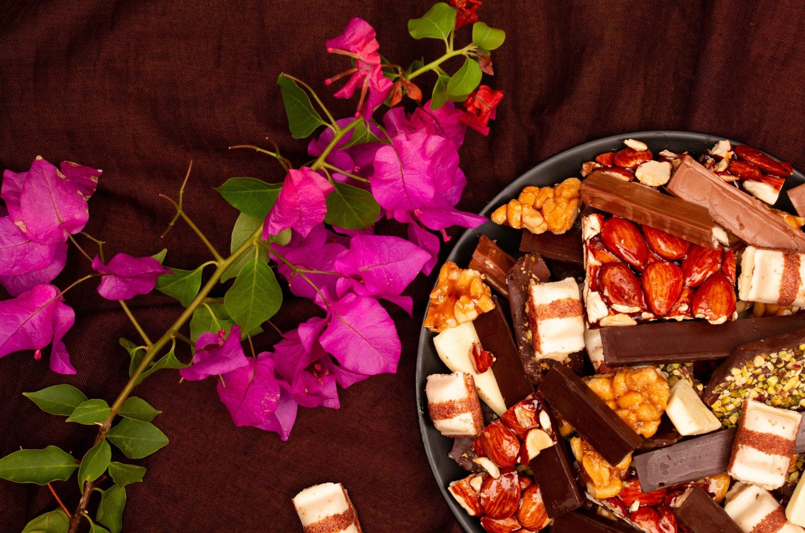 Assorted chocolates and nuts with pink flowers