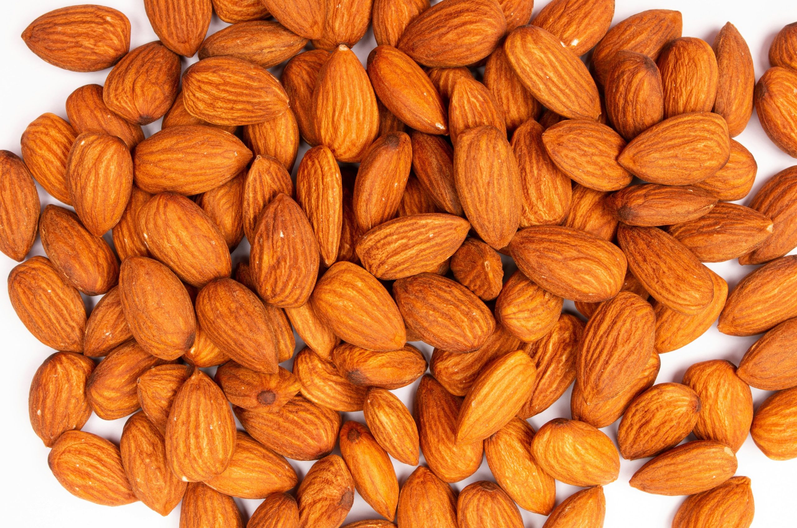 A pile of raw almonds on a white background