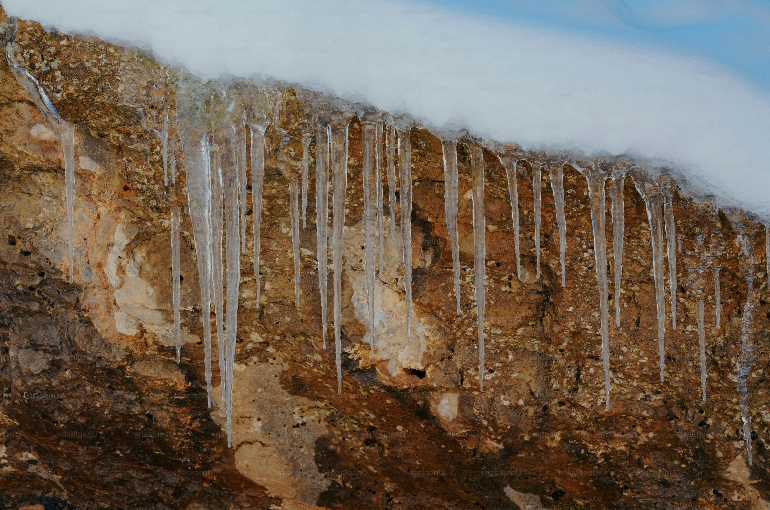 Icicles hanging from a rocky ledge with snow
