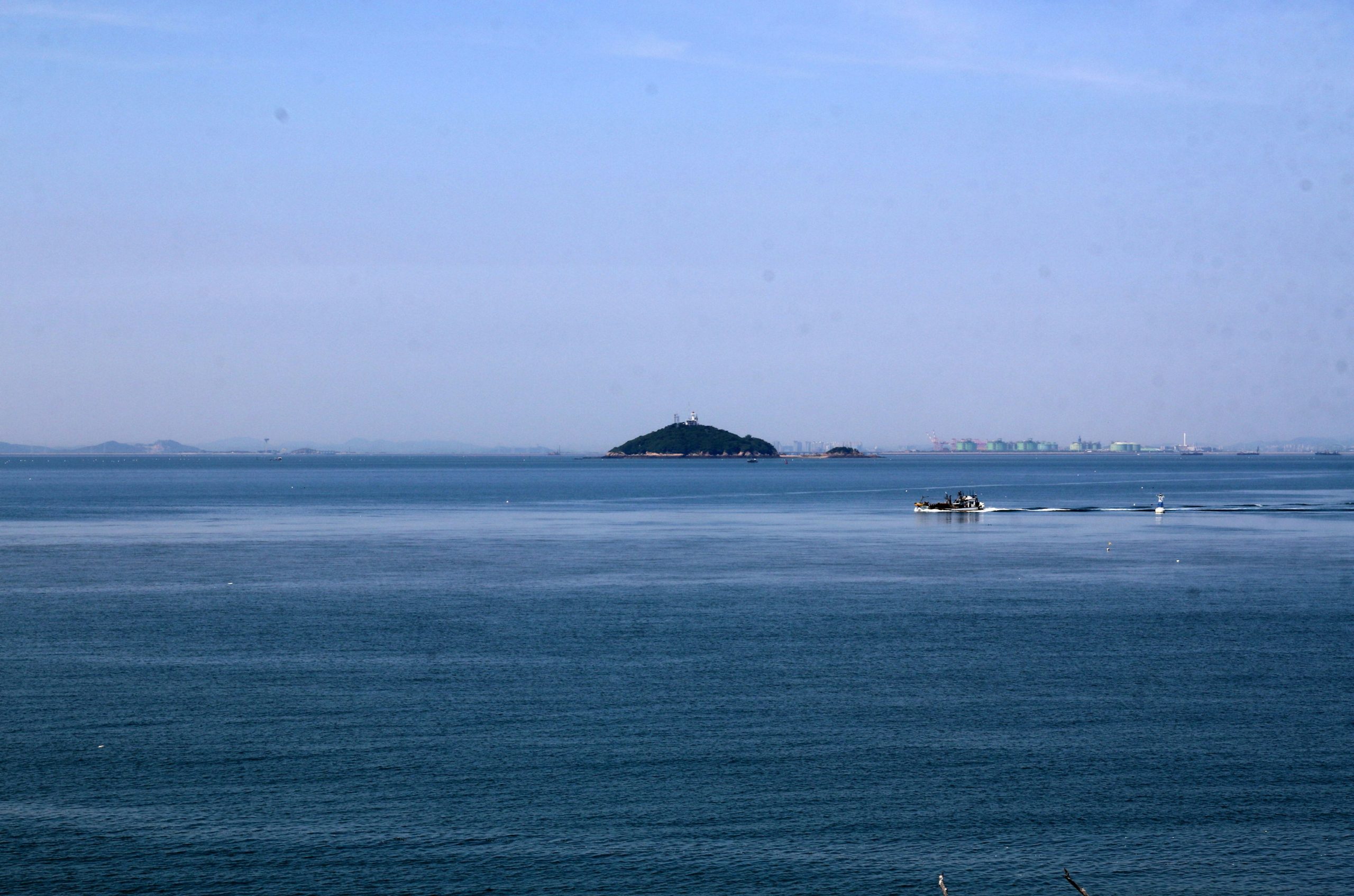 A distant island sits on the horizon over the ocean.