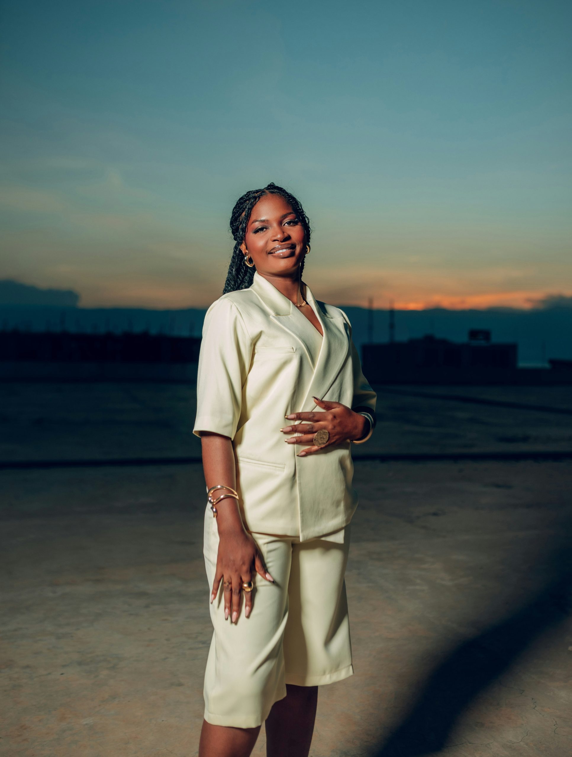 A woman in a cream suit smiles at sunset.