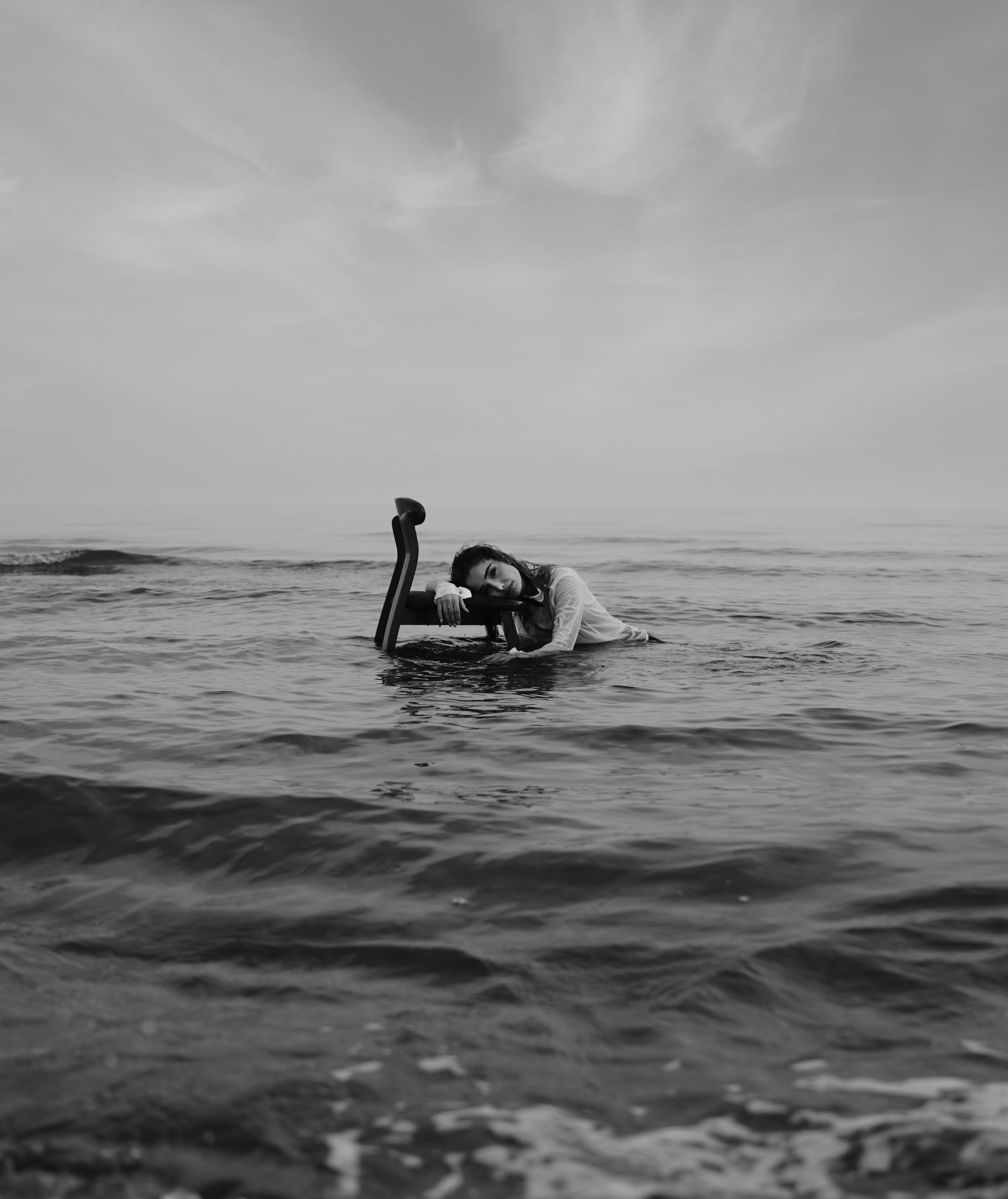 A woman lies in the ocean with a camera.