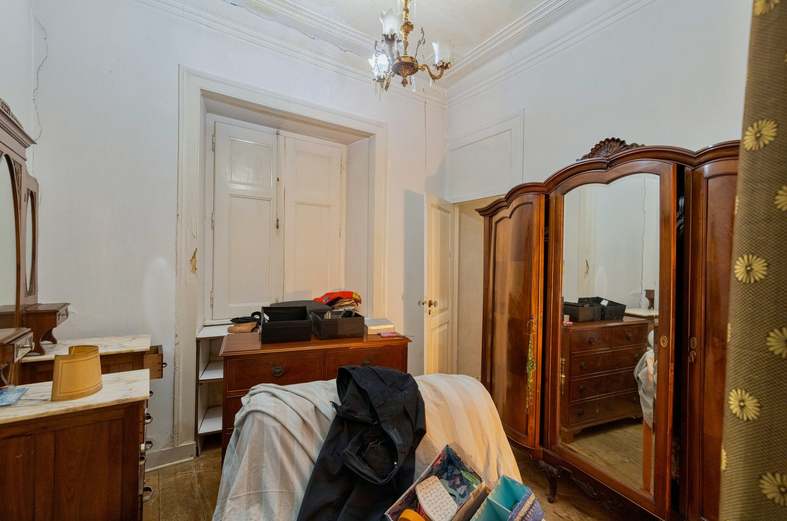 Bedroom with antique wooden furniture and chandelier.