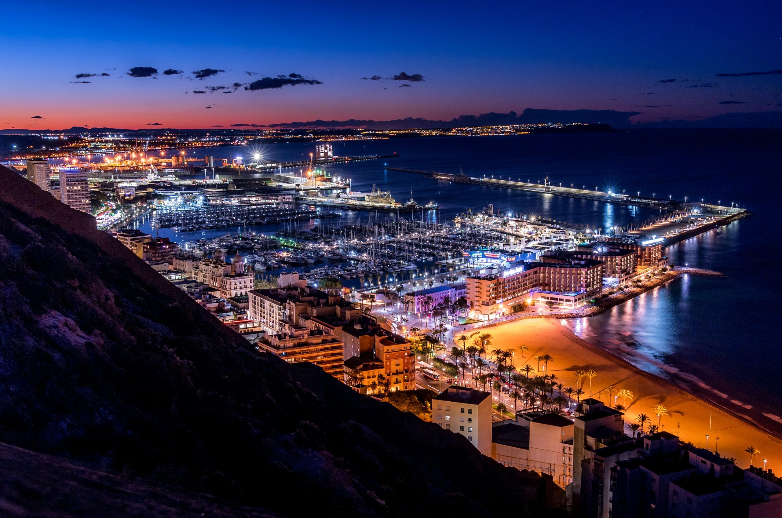 City lights sparkle along the coast at dusk.