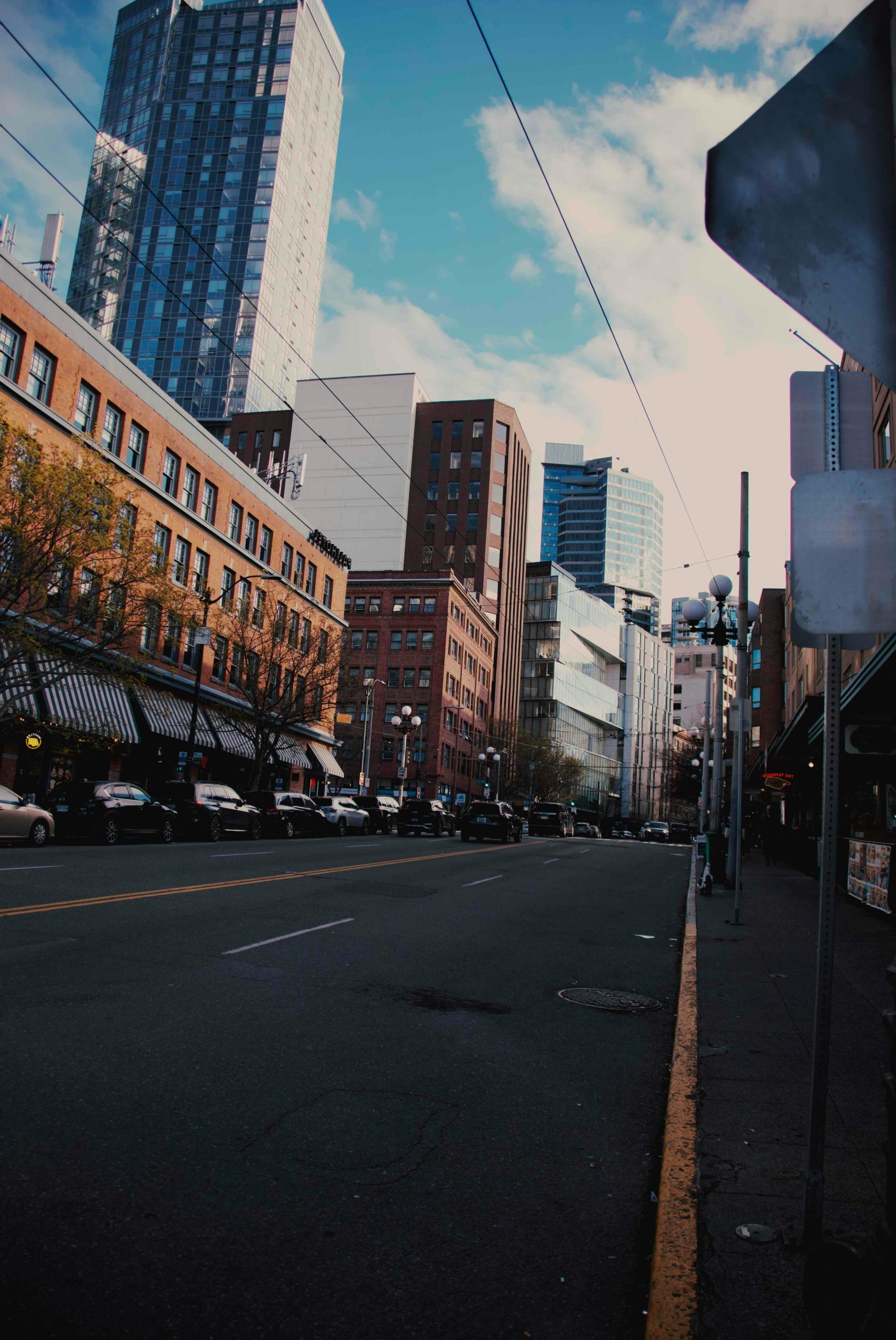 City street with cars and tall buildings under sky.