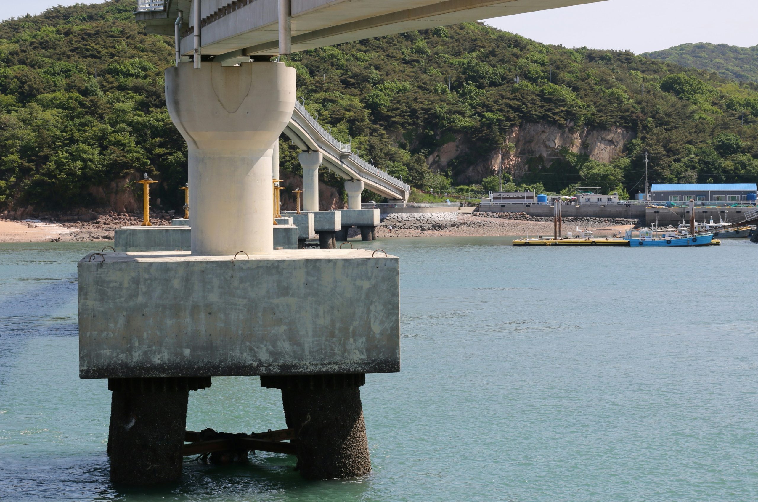 Concrete pier supports over blue water near shore.