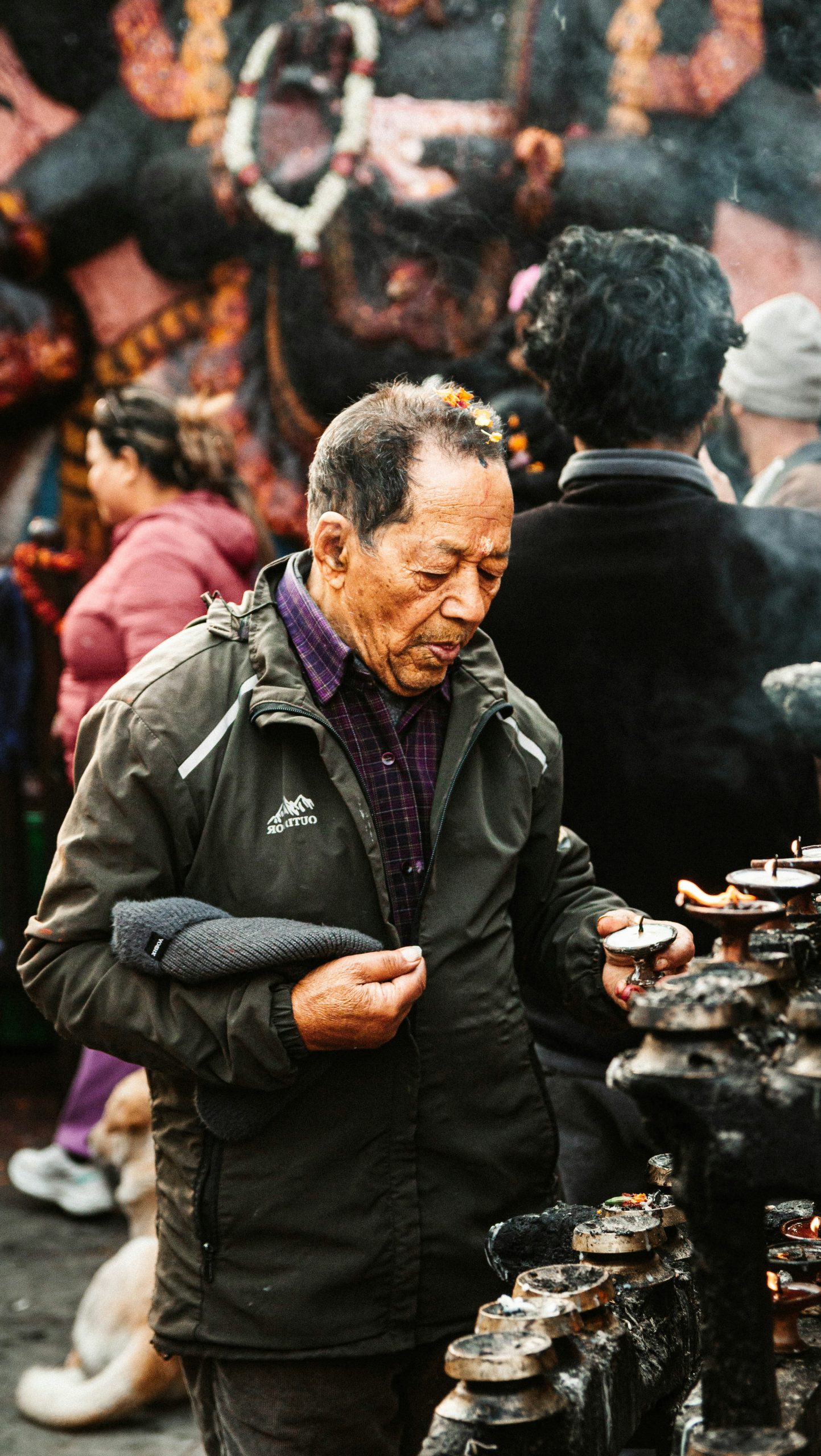 Elderly man lighting candles at a shrine
