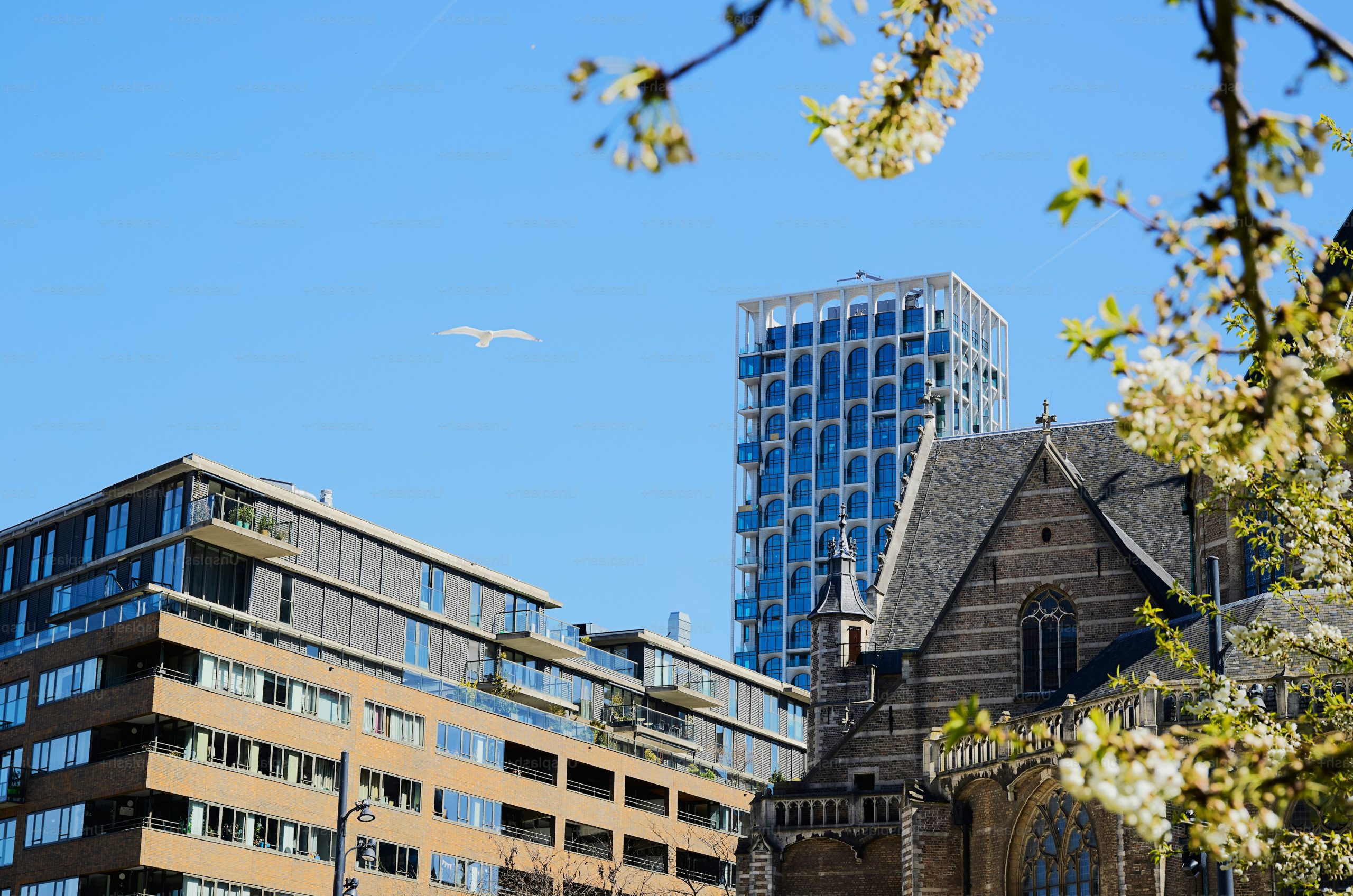 Modern buildings and old church under clear blue sky.
