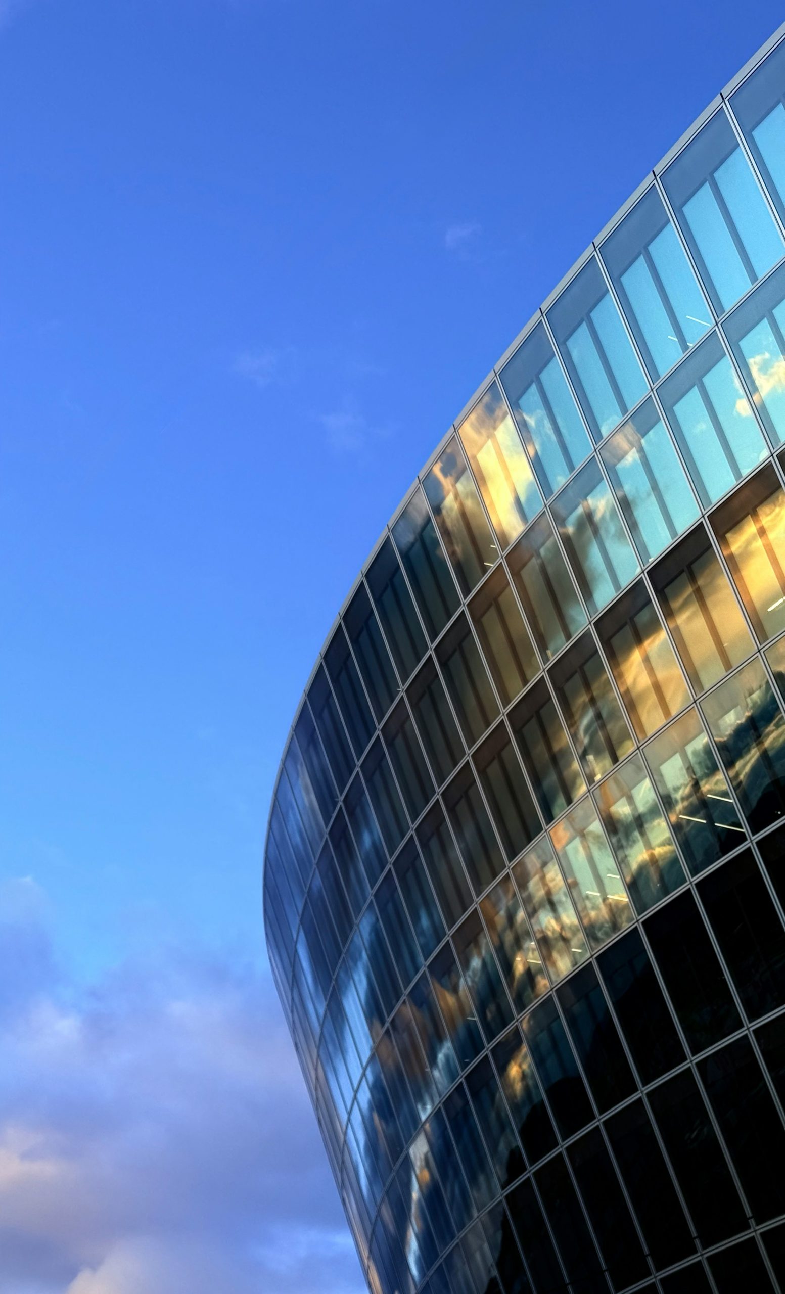 Modern glass building reflecting golden sunset against blue sky