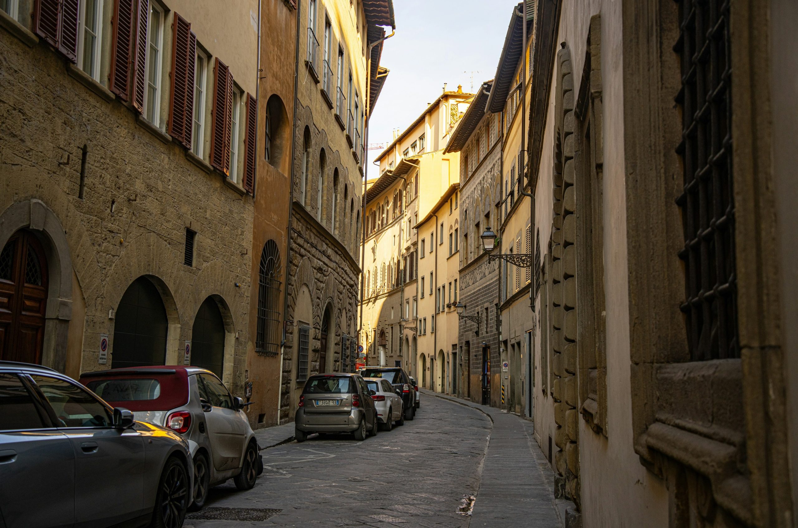 Narrow european street with parked cars and old buildings