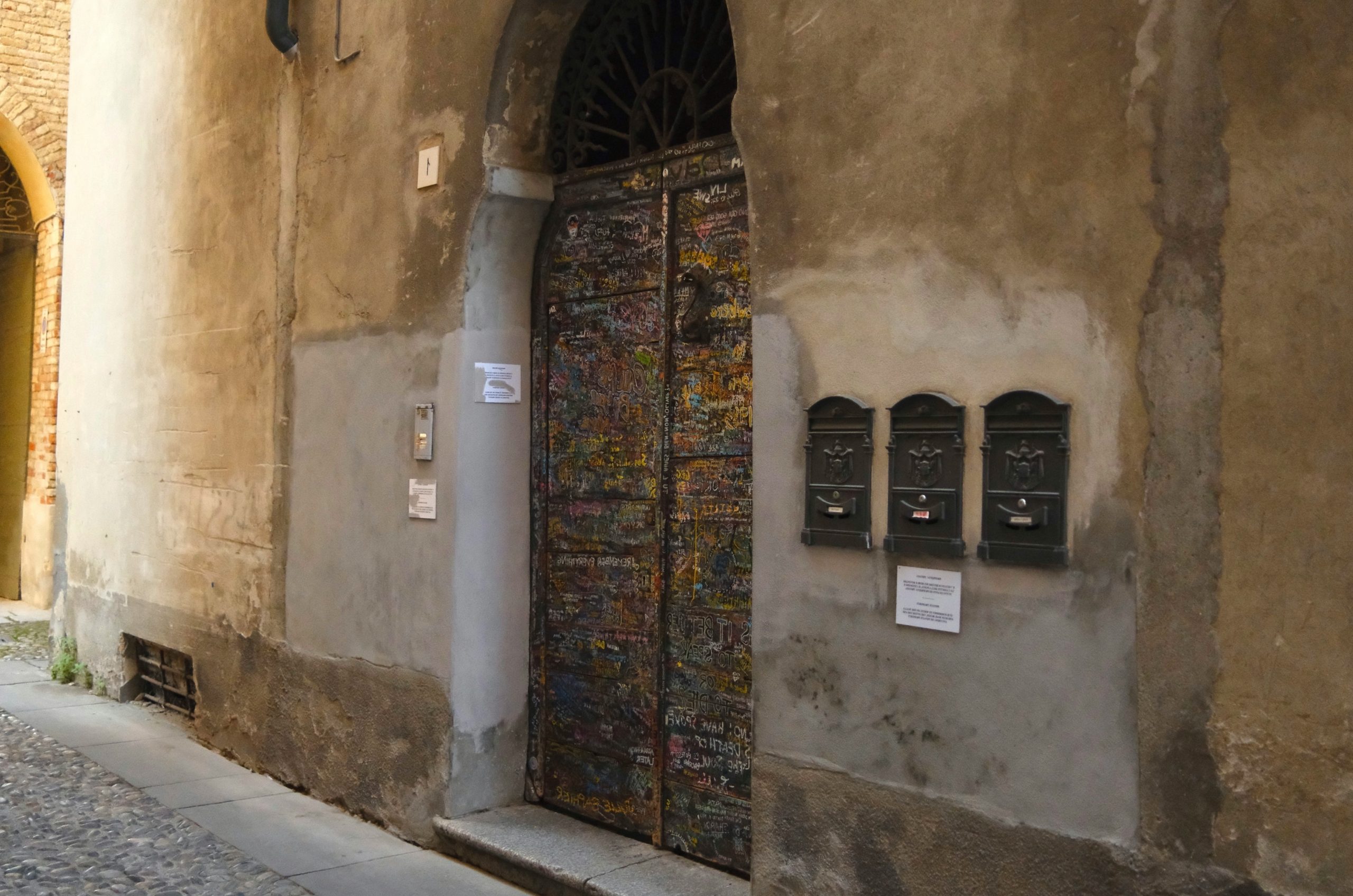 Ornate metal doors with three mailboxes on wall.
