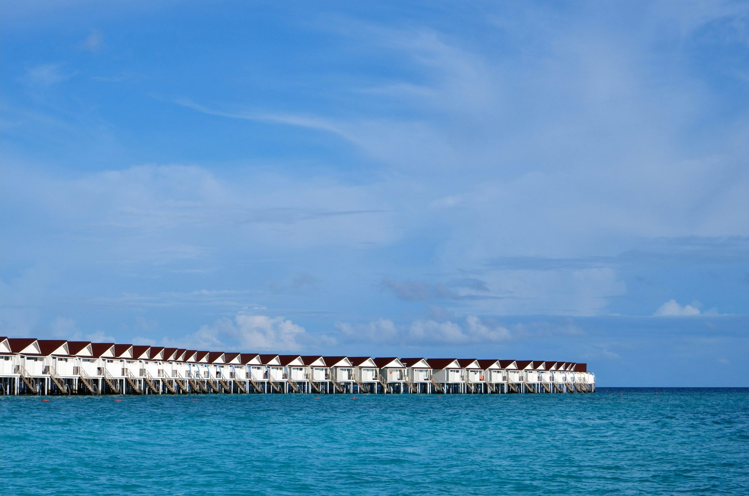 Overwater bungalows line a calm turquoise ocean