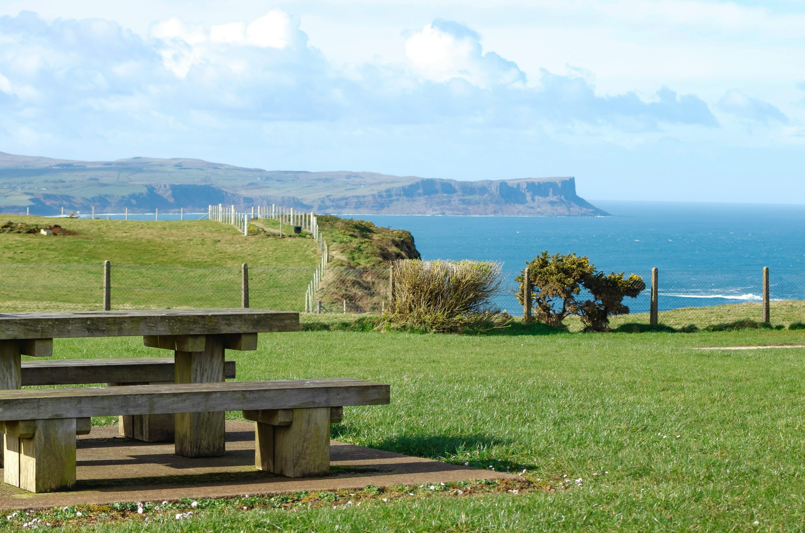 Picnic table overlooking a coastal landscape with ocean.