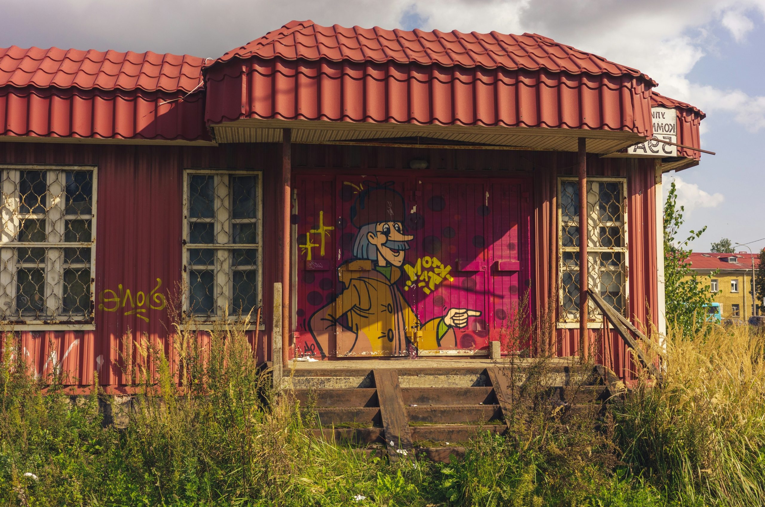 Red building with graffiti art of a character holding flowers.