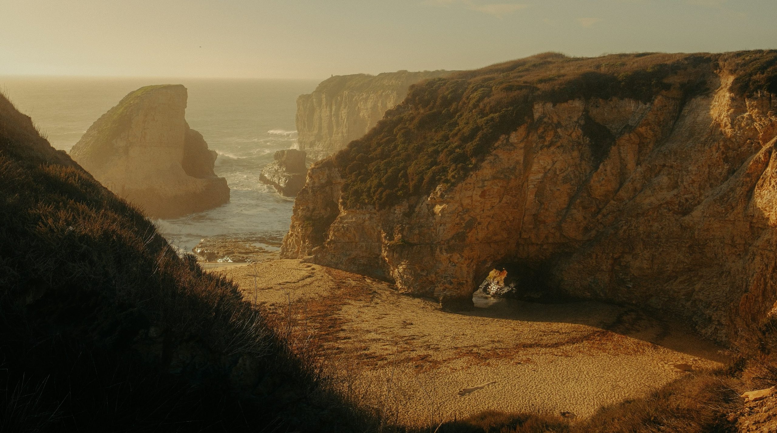 Rocky coastline with a sandy cove and ocean waves.