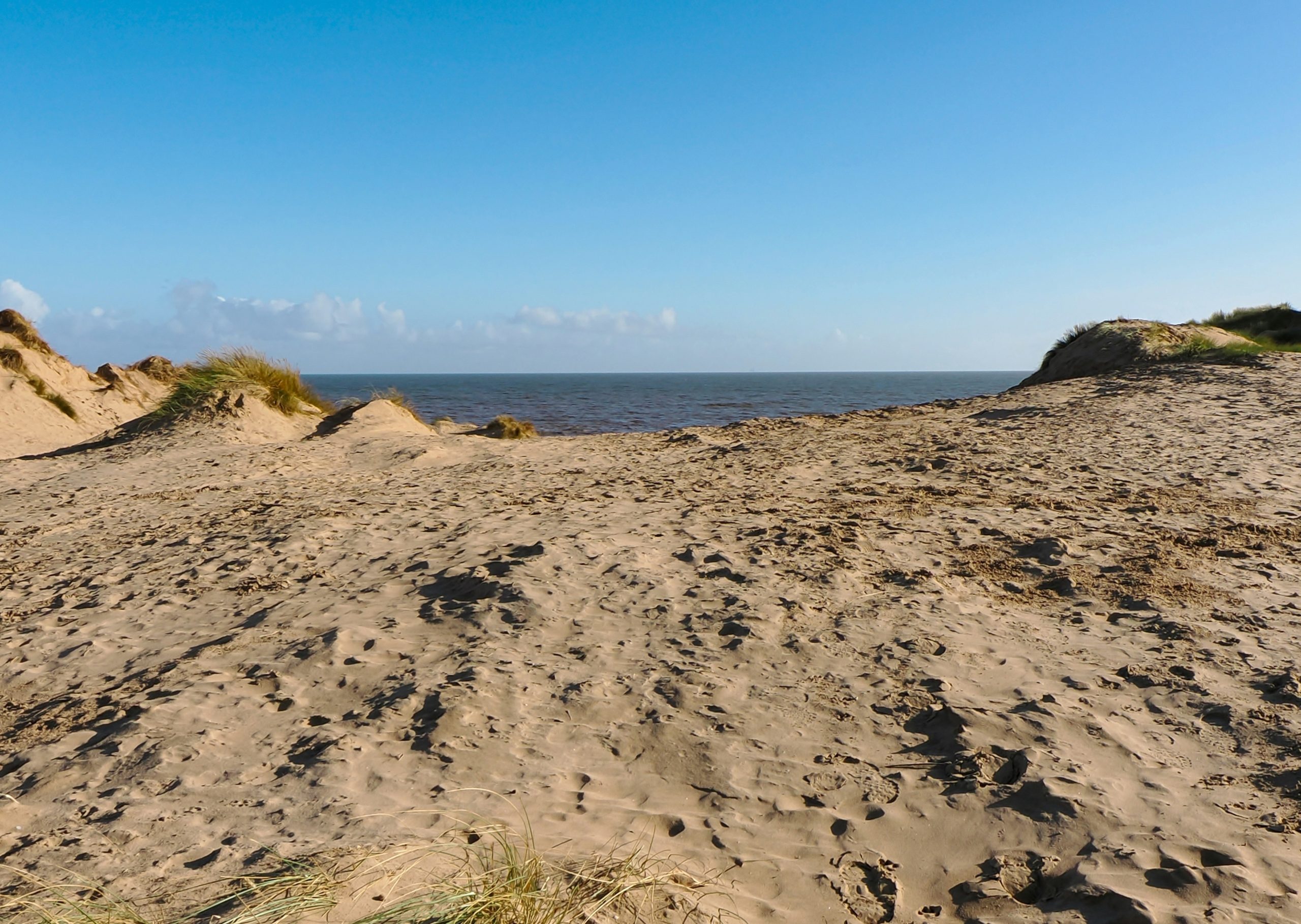 Sandy dunes with ocean and clear blue sky