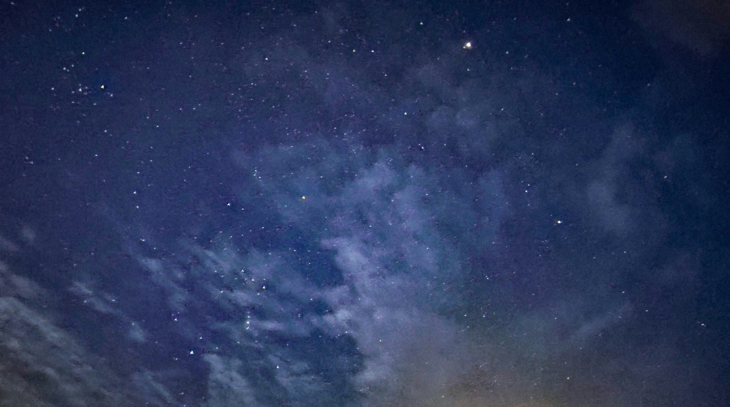 Starry night sky with clouds and distant constellations