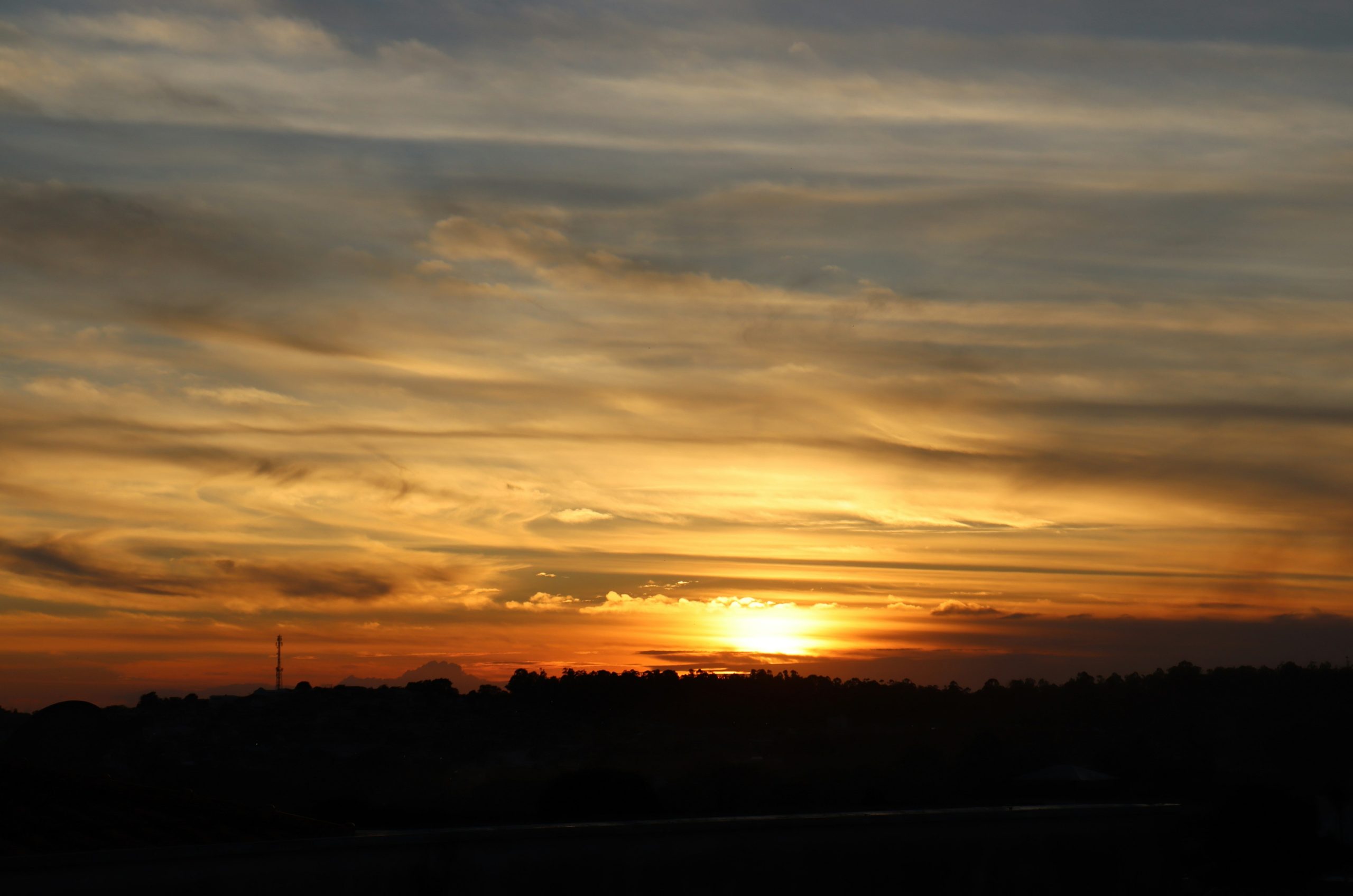 Sunset over a dark, silhouetted landscape.