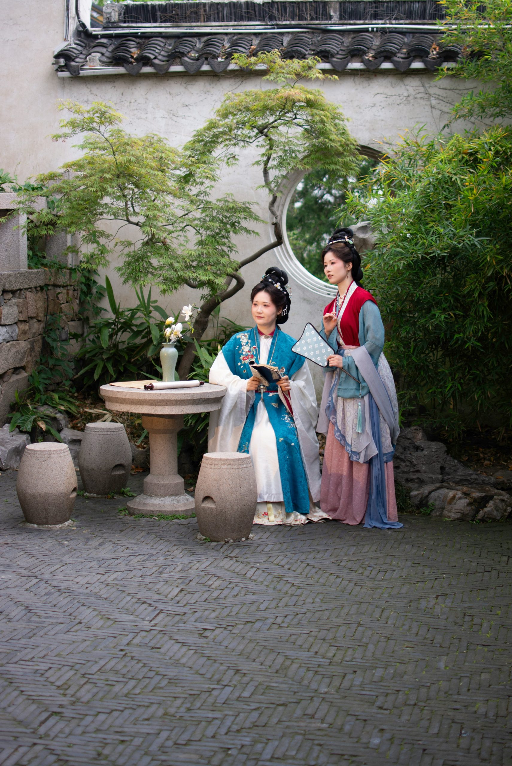 Two women in traditional chinese clothing in a garden.