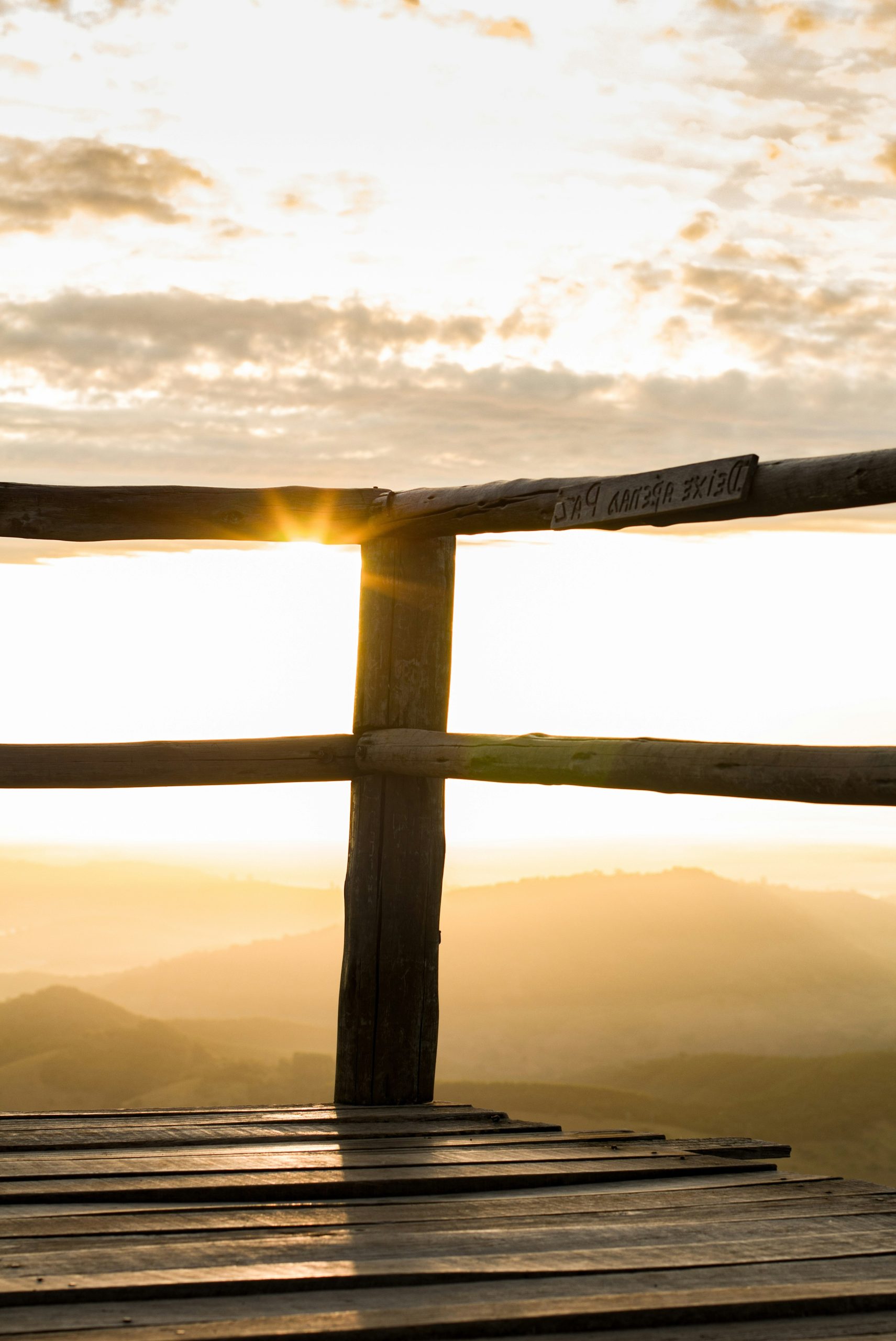 Wooden deck overlooks misty mountains at sunrise