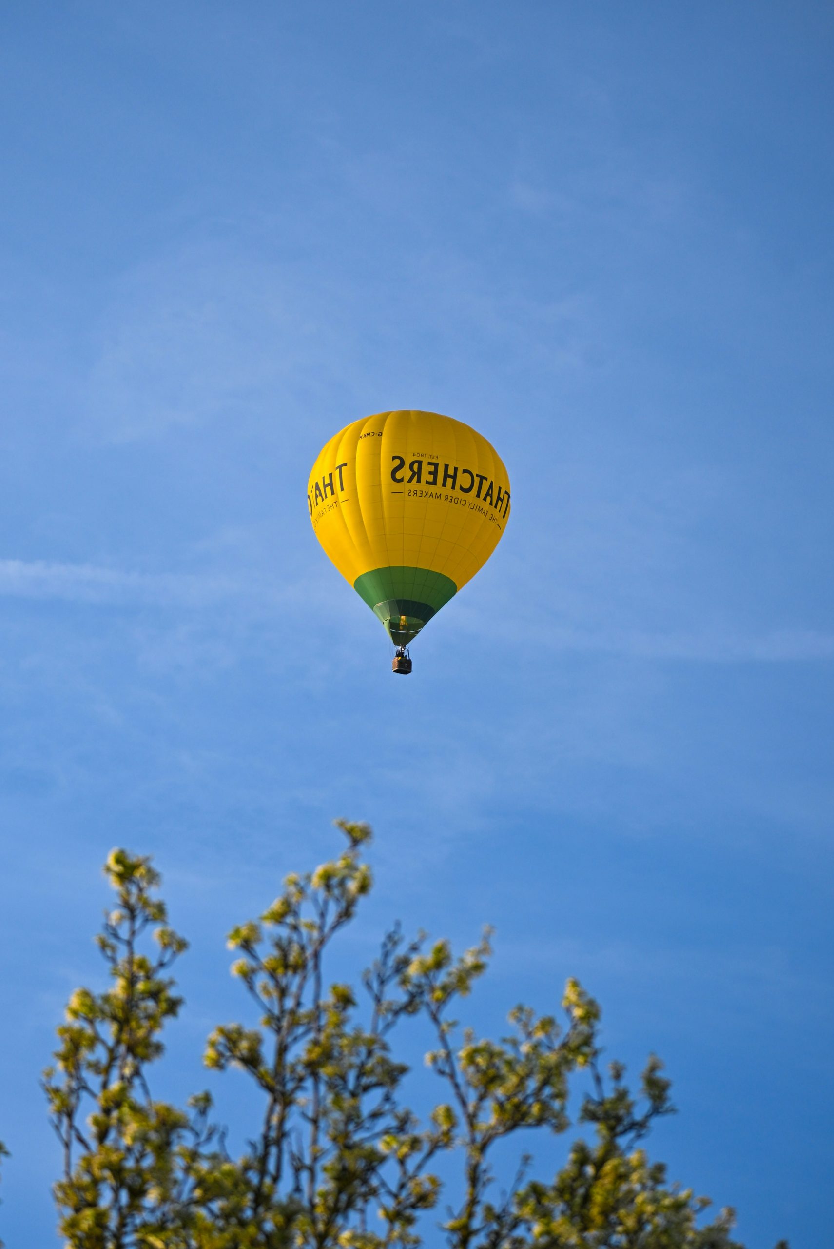 Yellow hot air balloon against a clear blue sky.