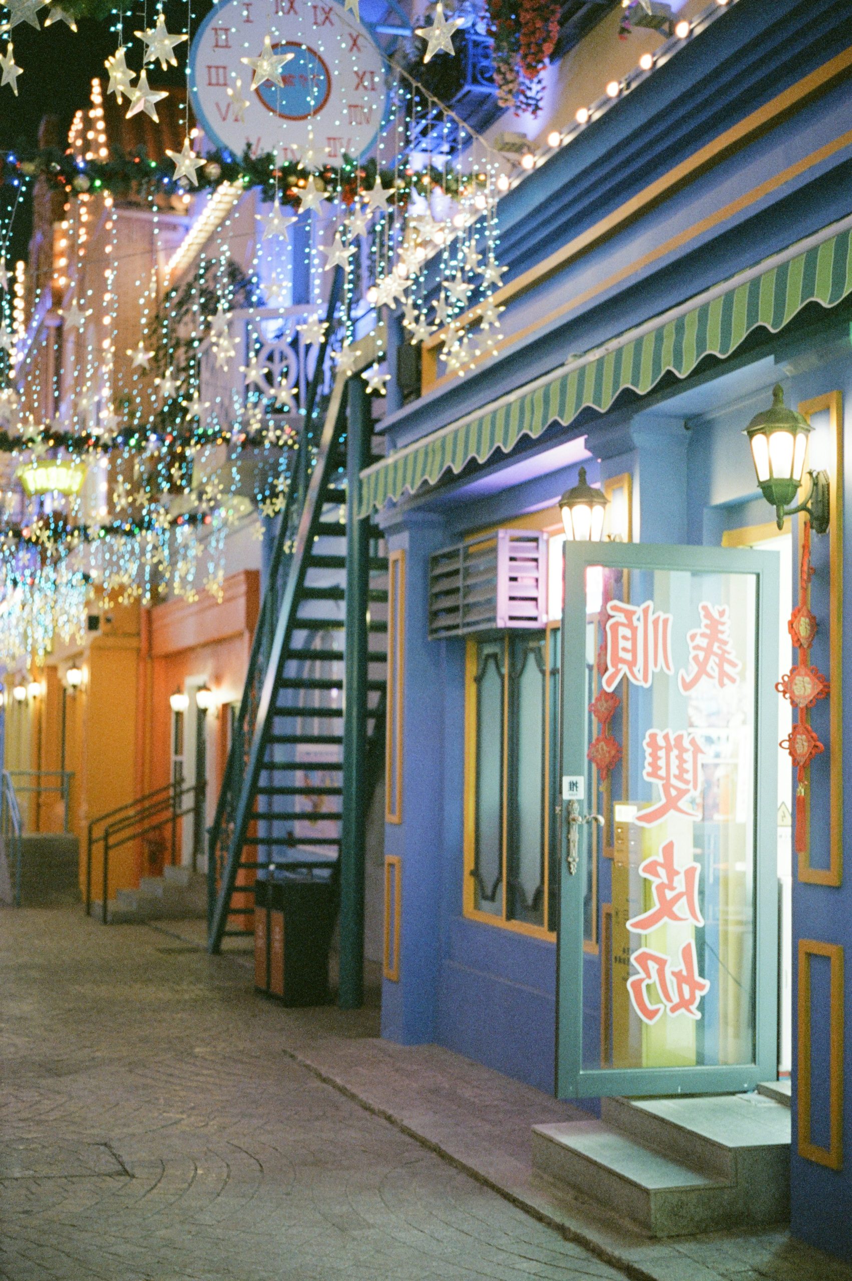 A festive street with colorful buildings and sparkling string lights.