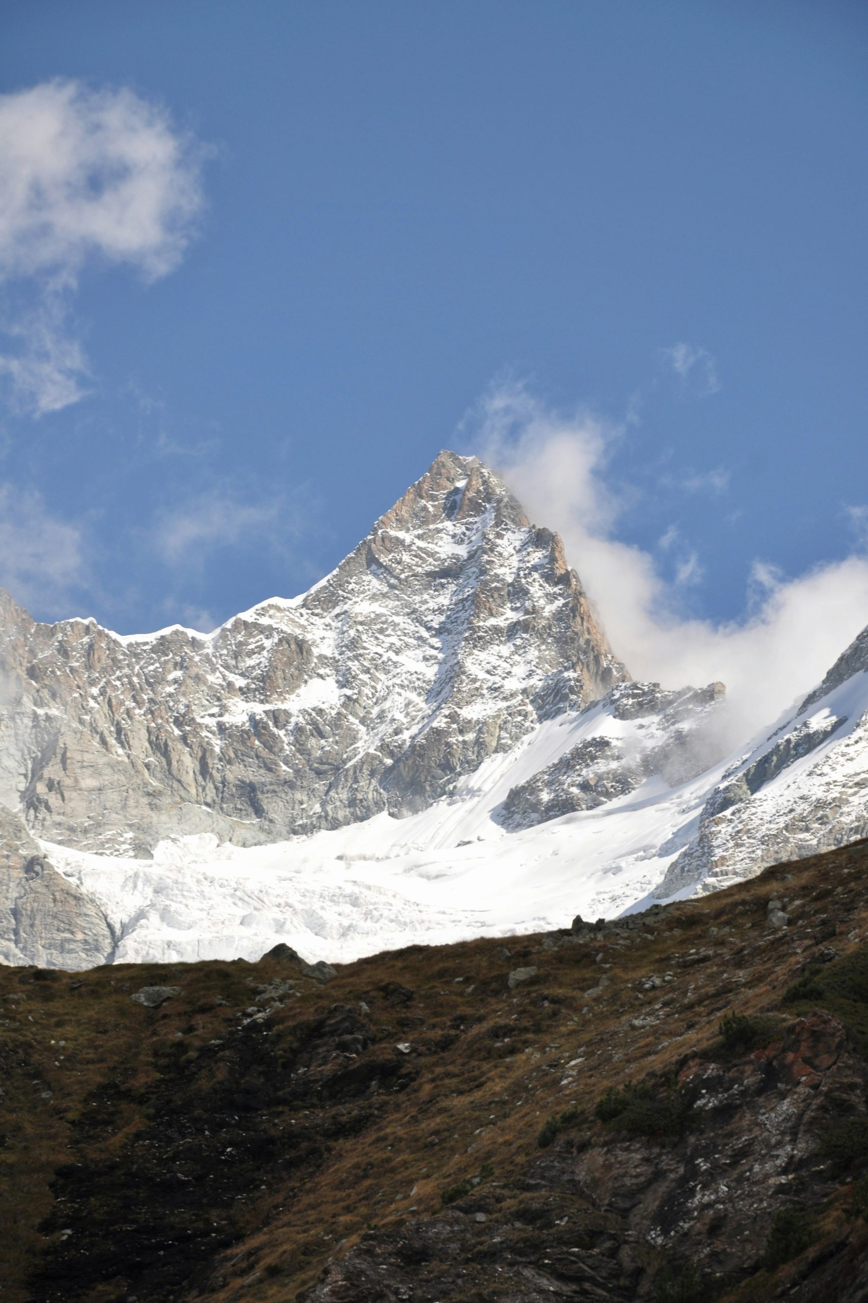 A majestic snow-capped mountain peak under a blue sky.