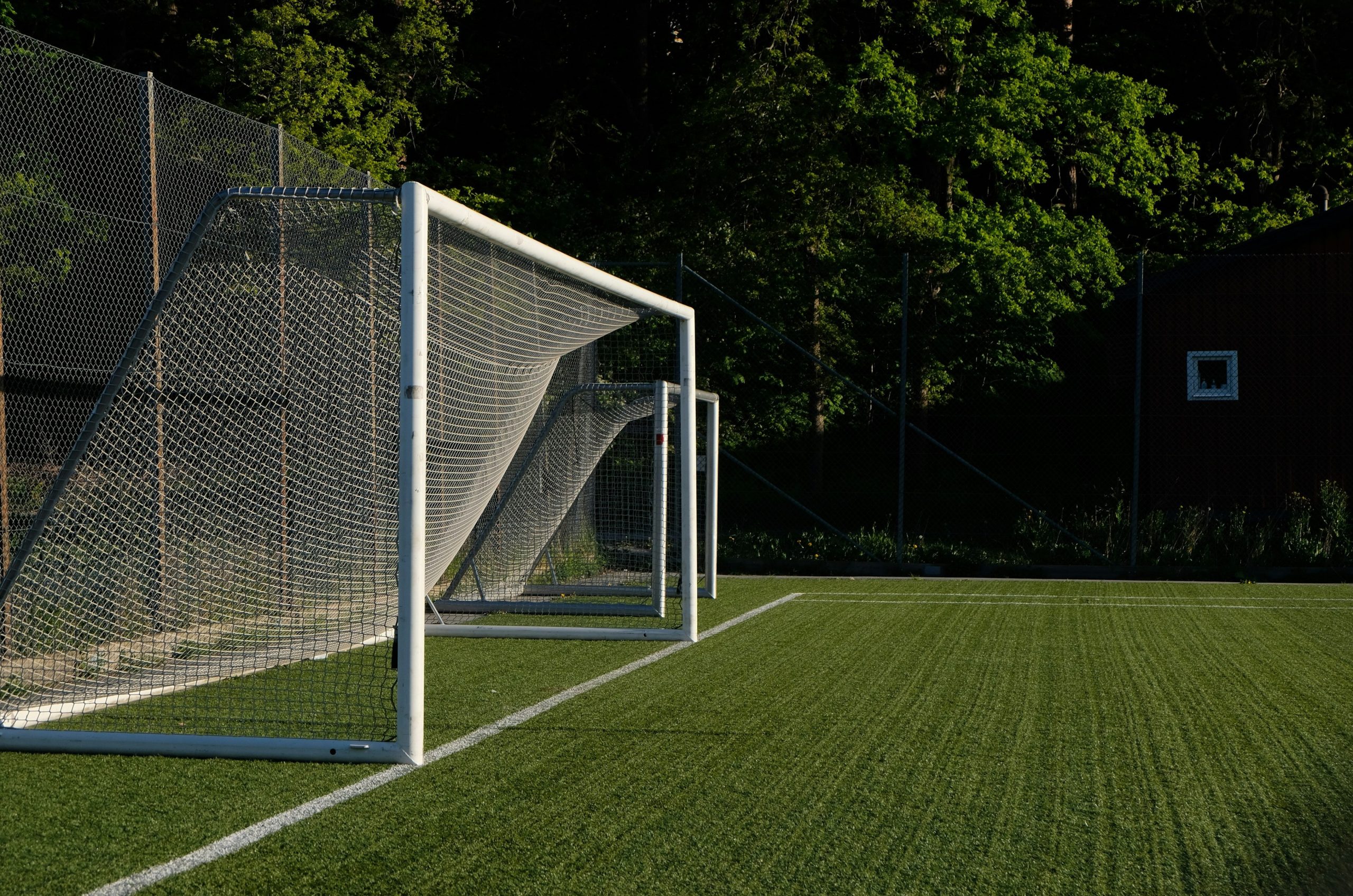 A white soccer goal on a green artificial turf field.