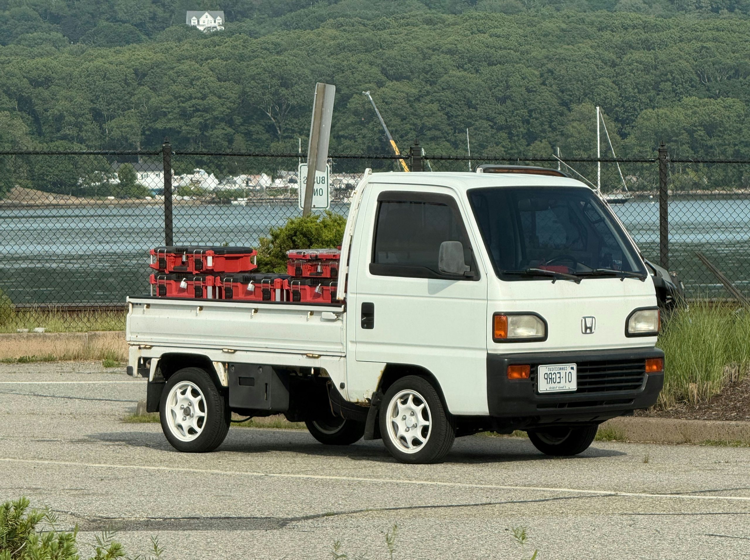 A white utility truck with red crates parked near water.