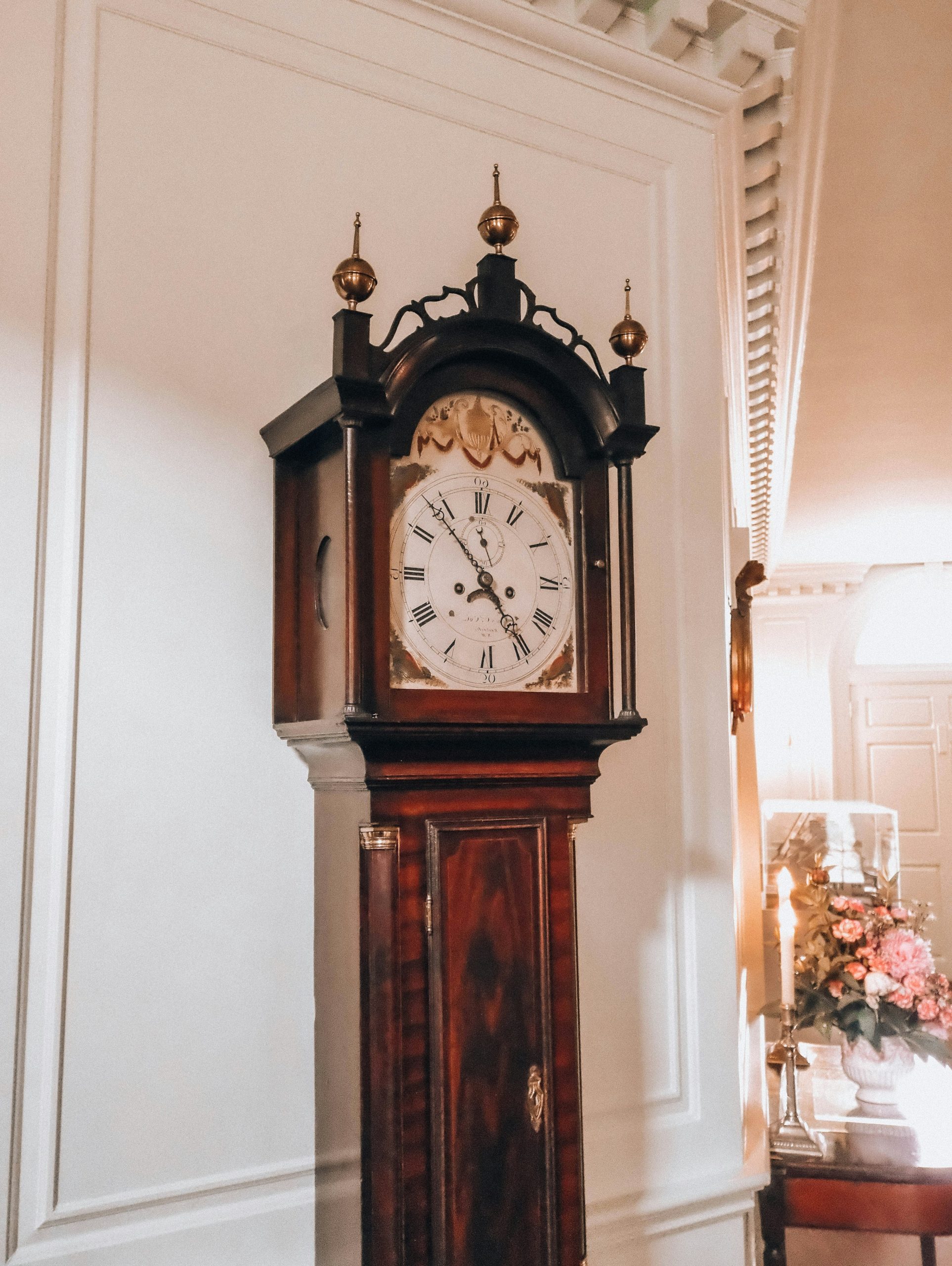 An antique wooden grandfather clock stands in a well-decorated room.