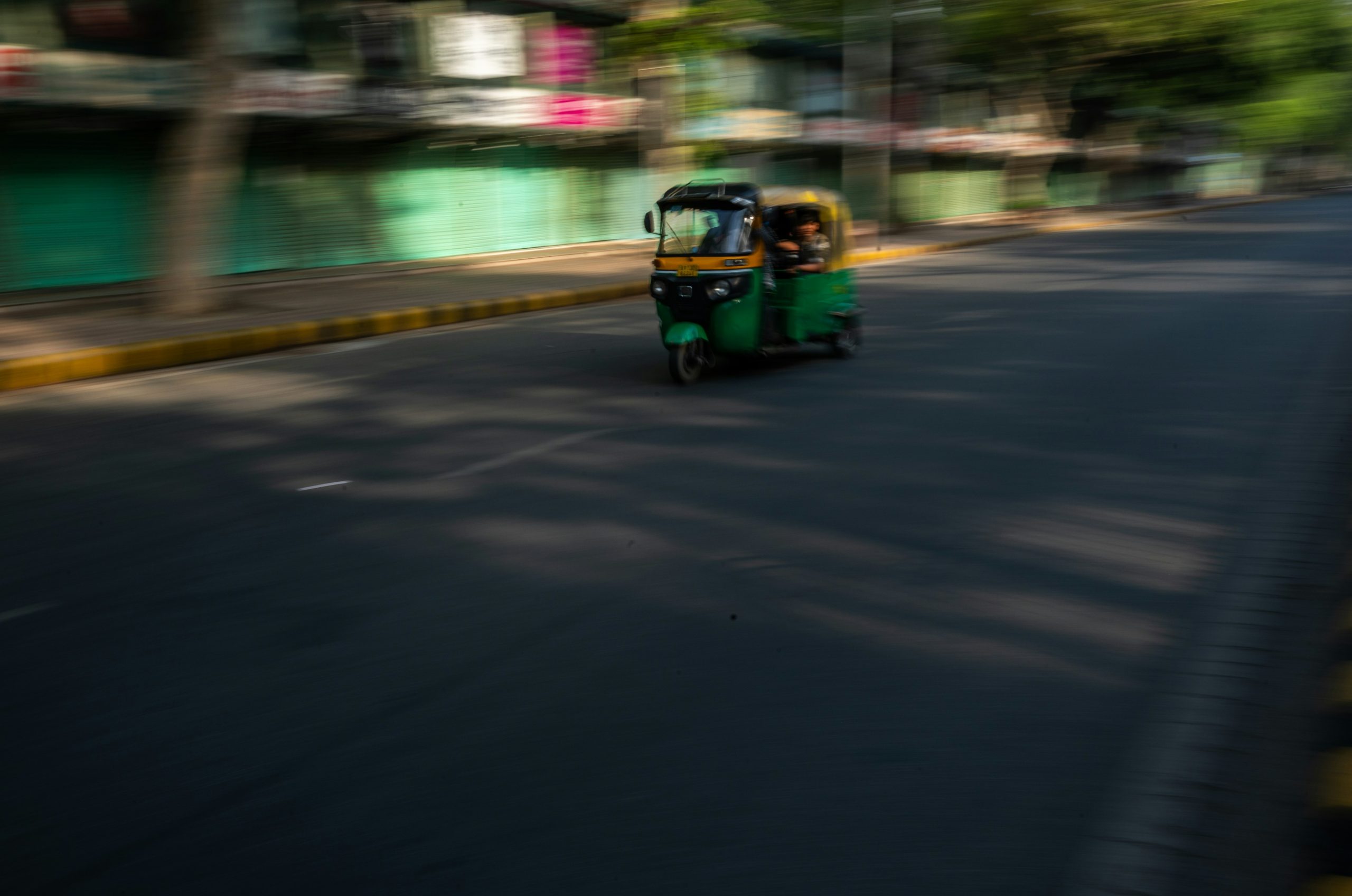 An auto rickshaw drives down a blurred street.
