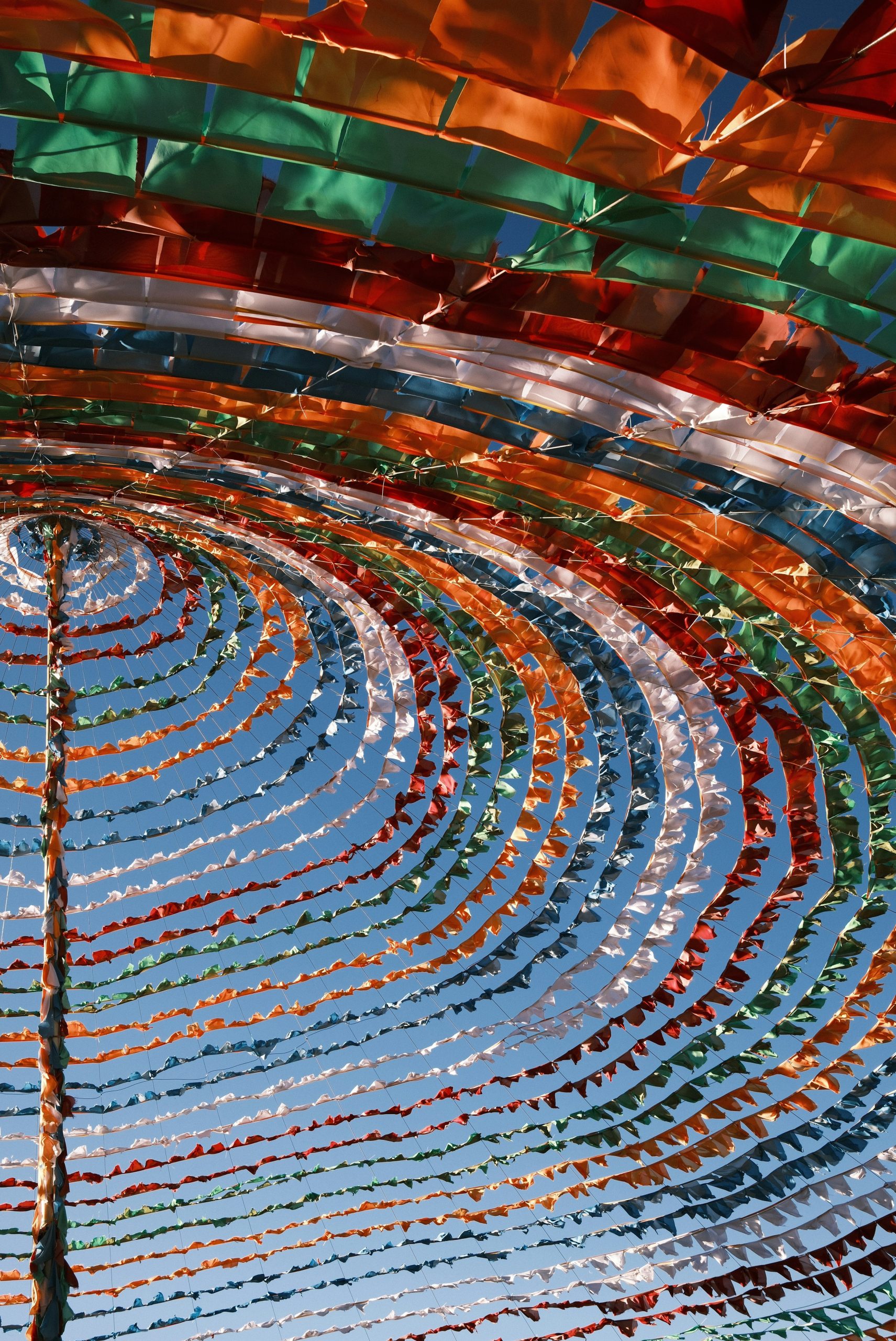 Colorful flags form a circular canopy against blue sky