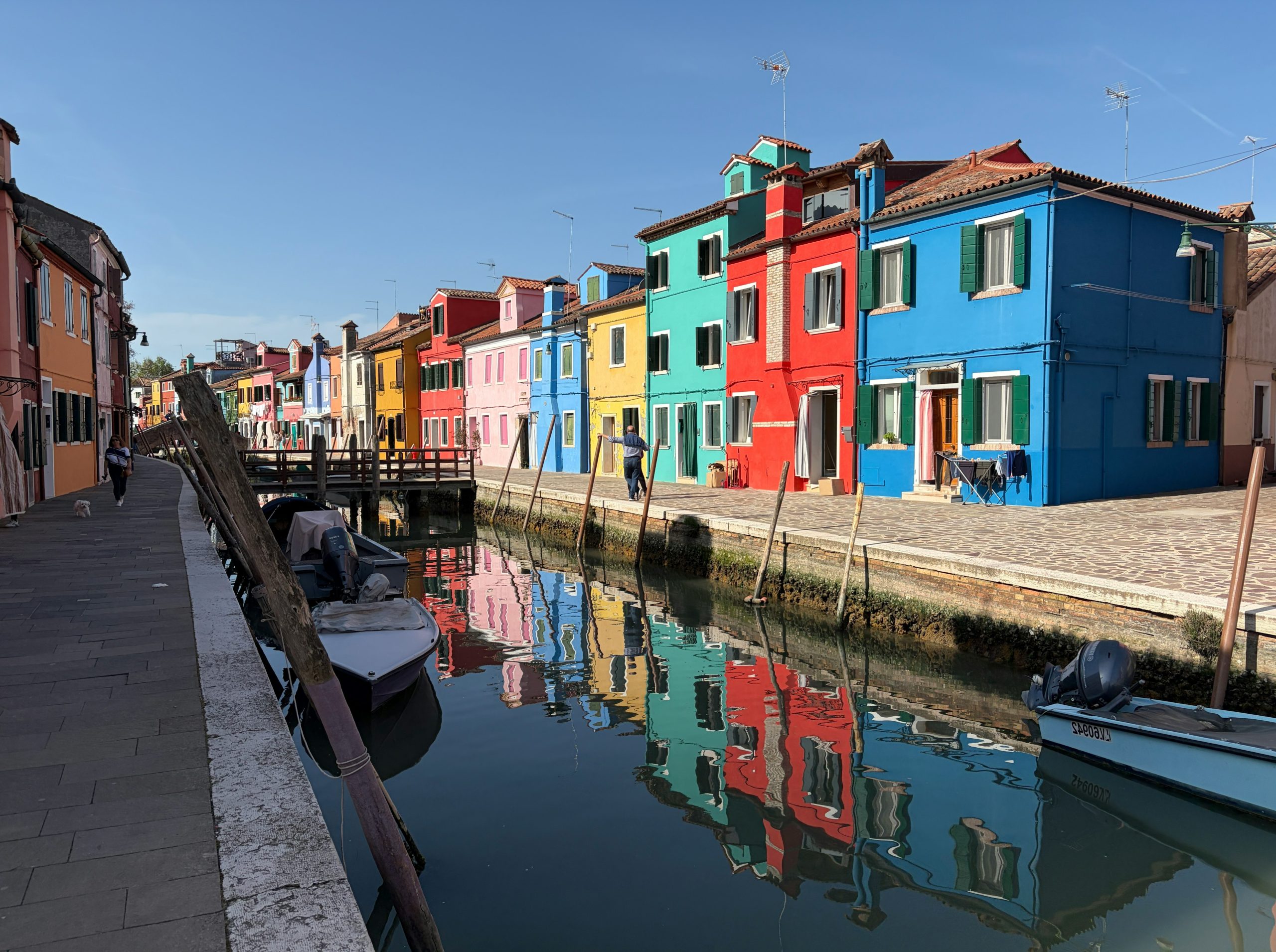 Colorful houses line a canal with reflections.