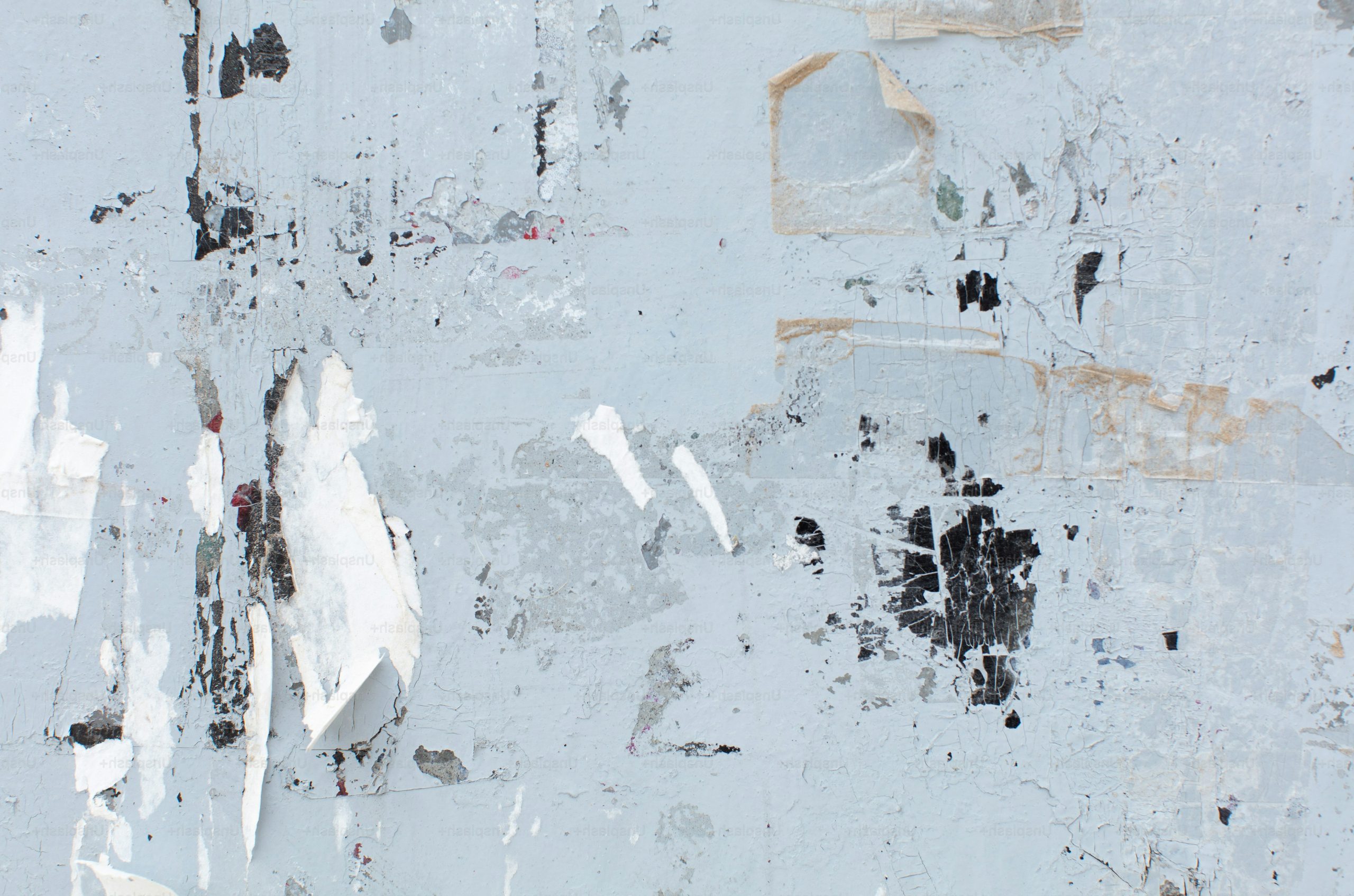 Distressed white wall with peeling paper and dark grunge marks.