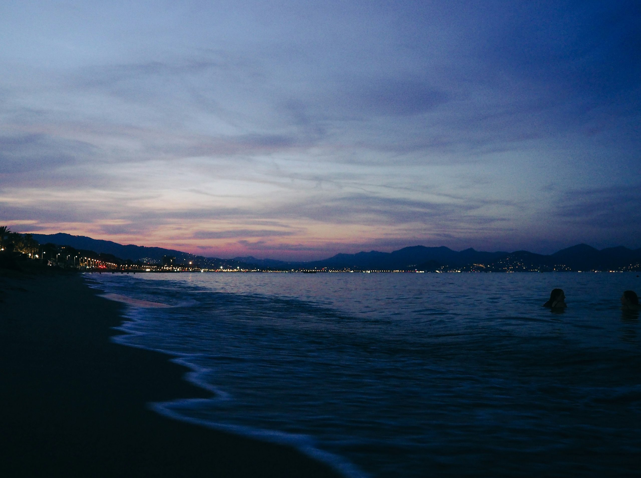 Dusk settles over a coastal town with lights twinkling
