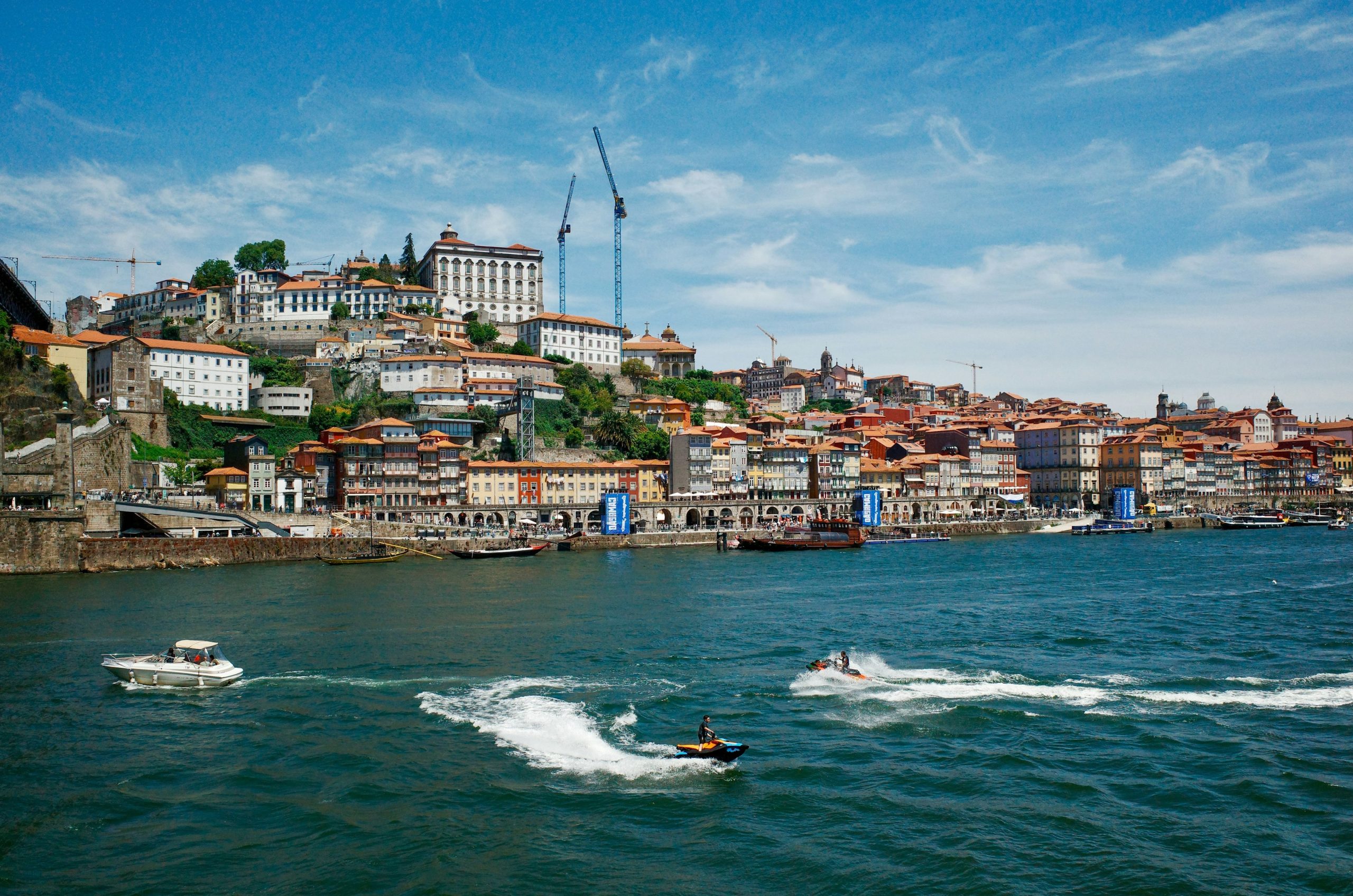 Historic city on a river with boats and blue sky.