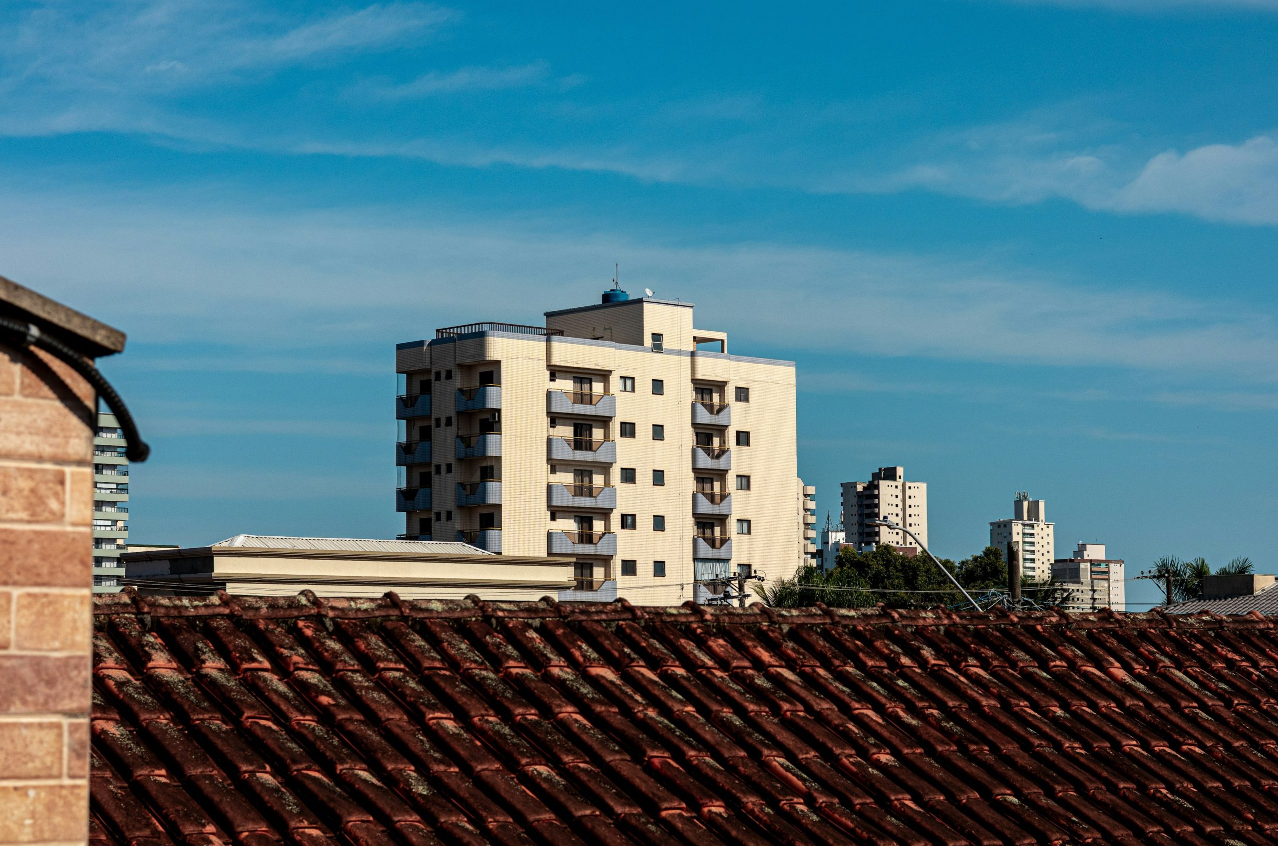 Modern buildings rise above a terracotta roof against blue sky.