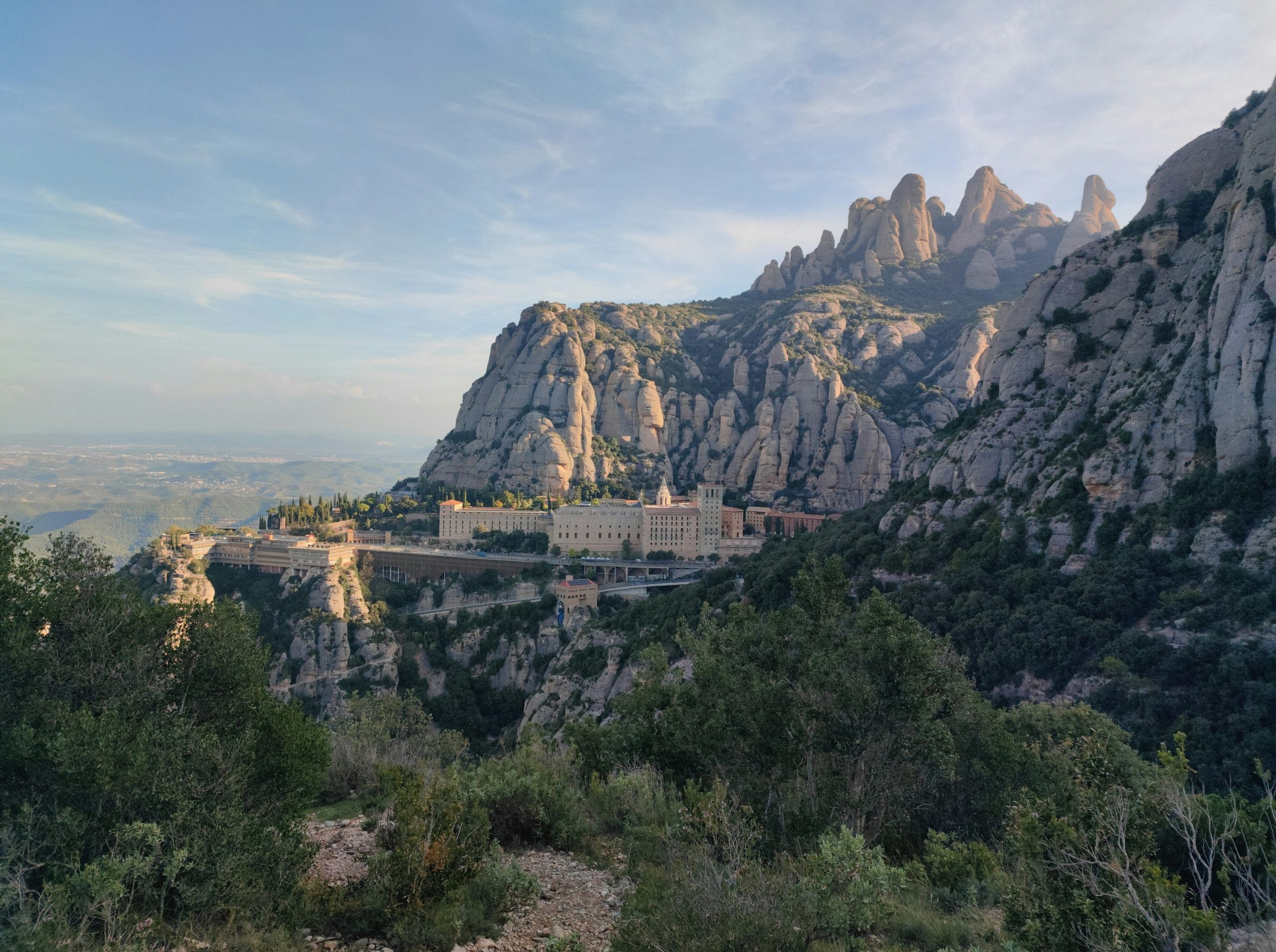 Monastery nestled in rugged mountains under a blue sky.