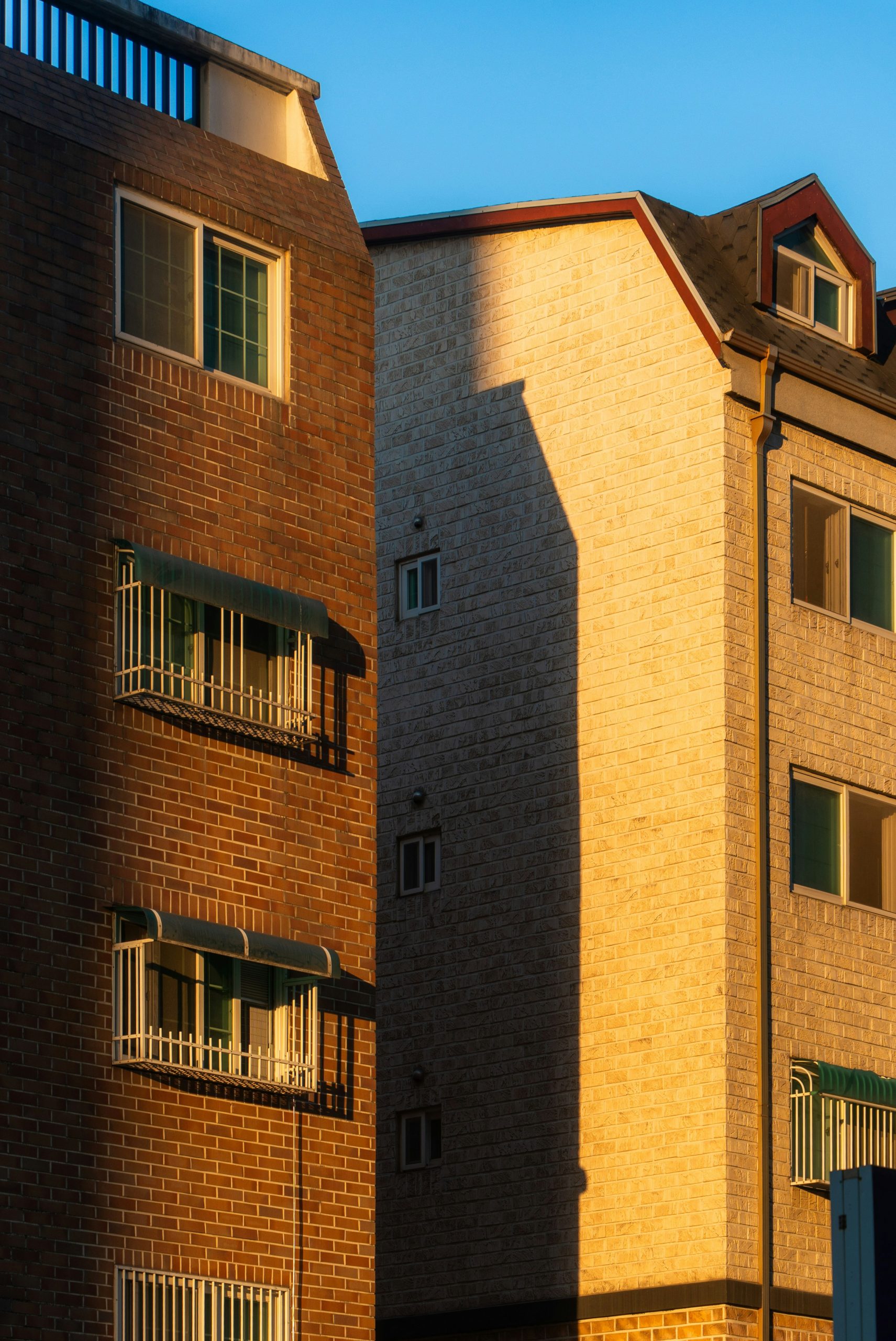 Sunlight and shadow on two brick apartment buildings.