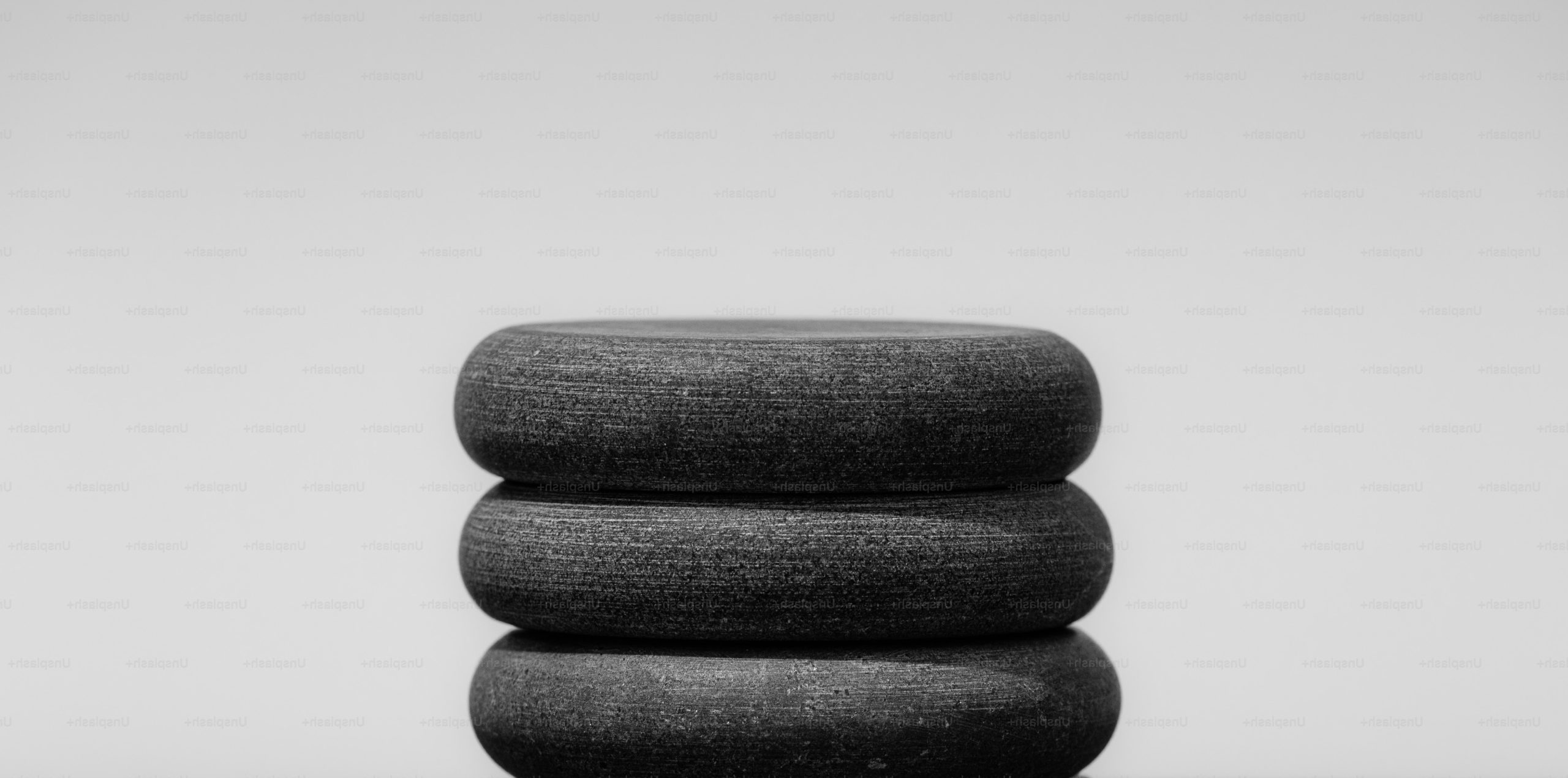 Three stacked dark stones against a light background.