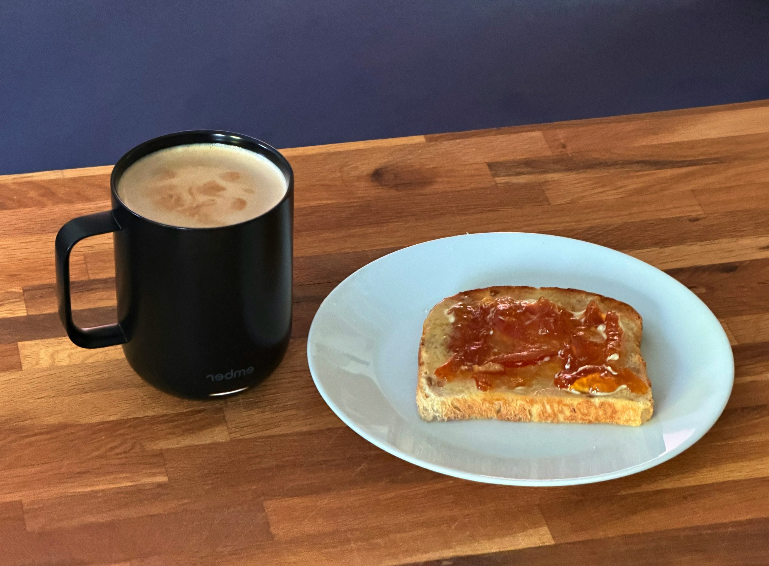 Toast with jam and a black coffee mug on wood.