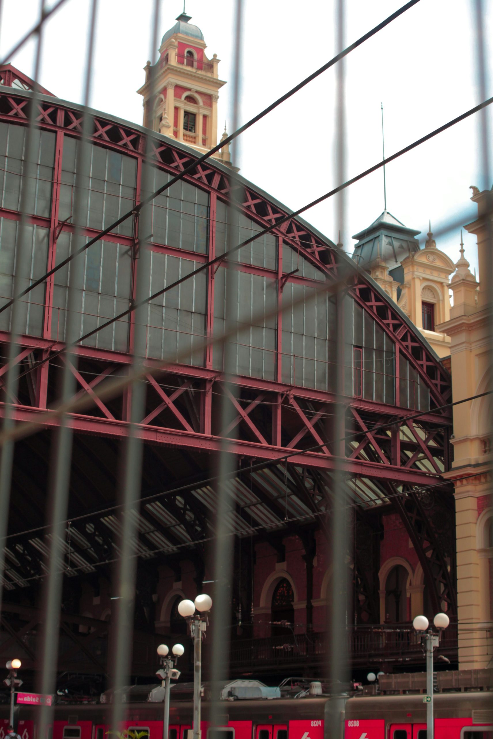 Train station with red roof and tower behind a fence.