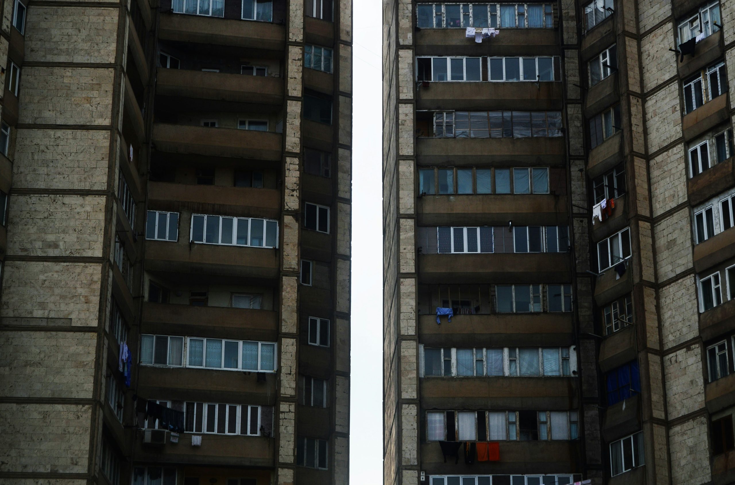 Two weathered apartment buildings with numerous windows and balconies.