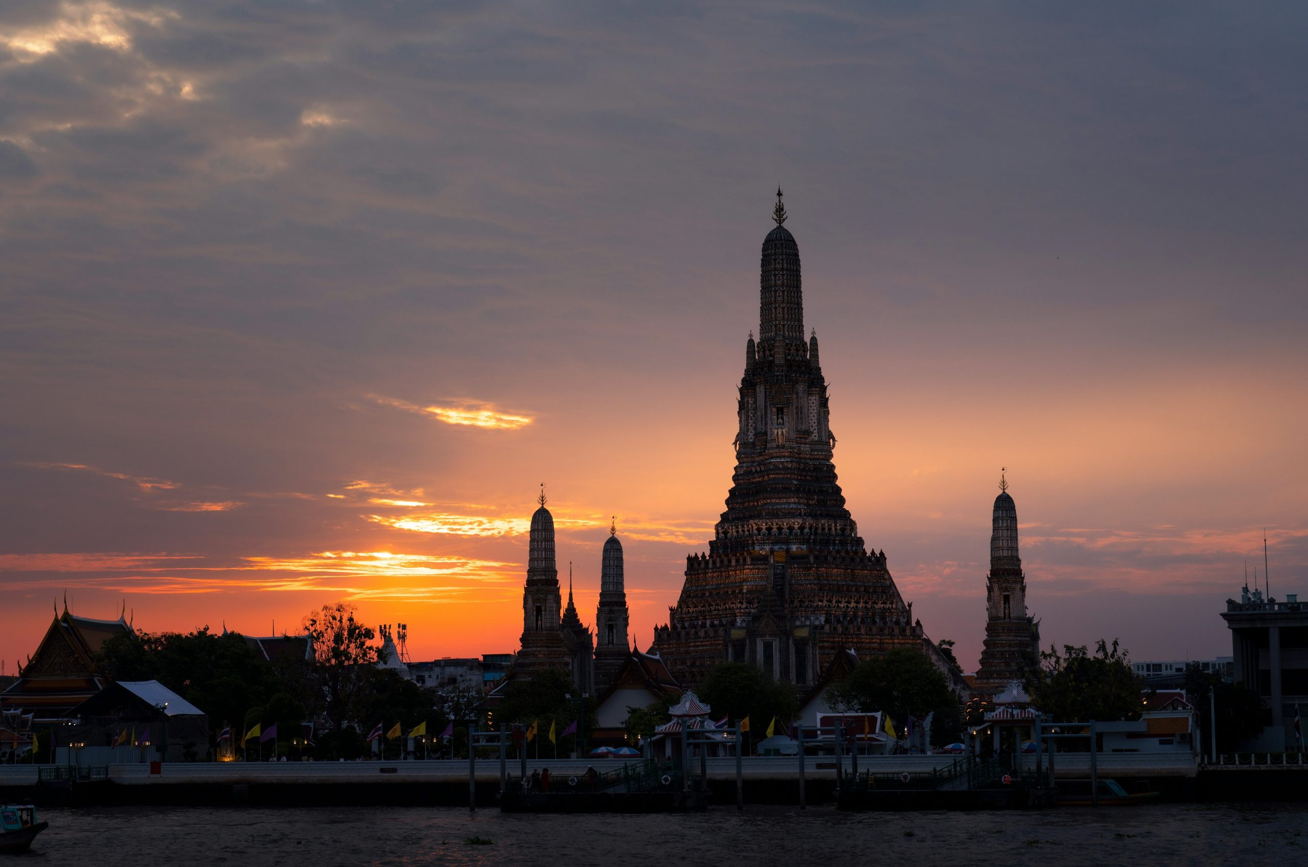 Wat arun temple silhouetted against a vibrant sunset sky.