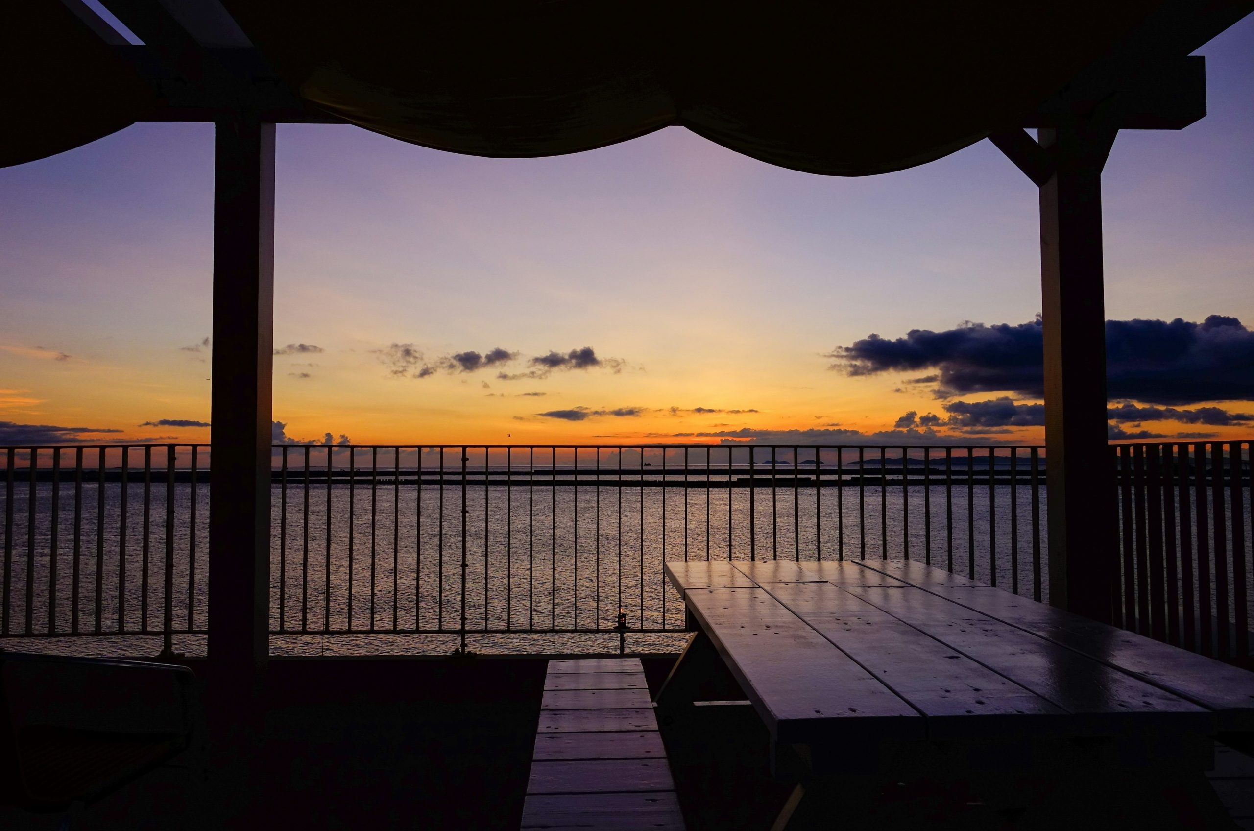 A beautiful sunset over the ocean from a covered patio.