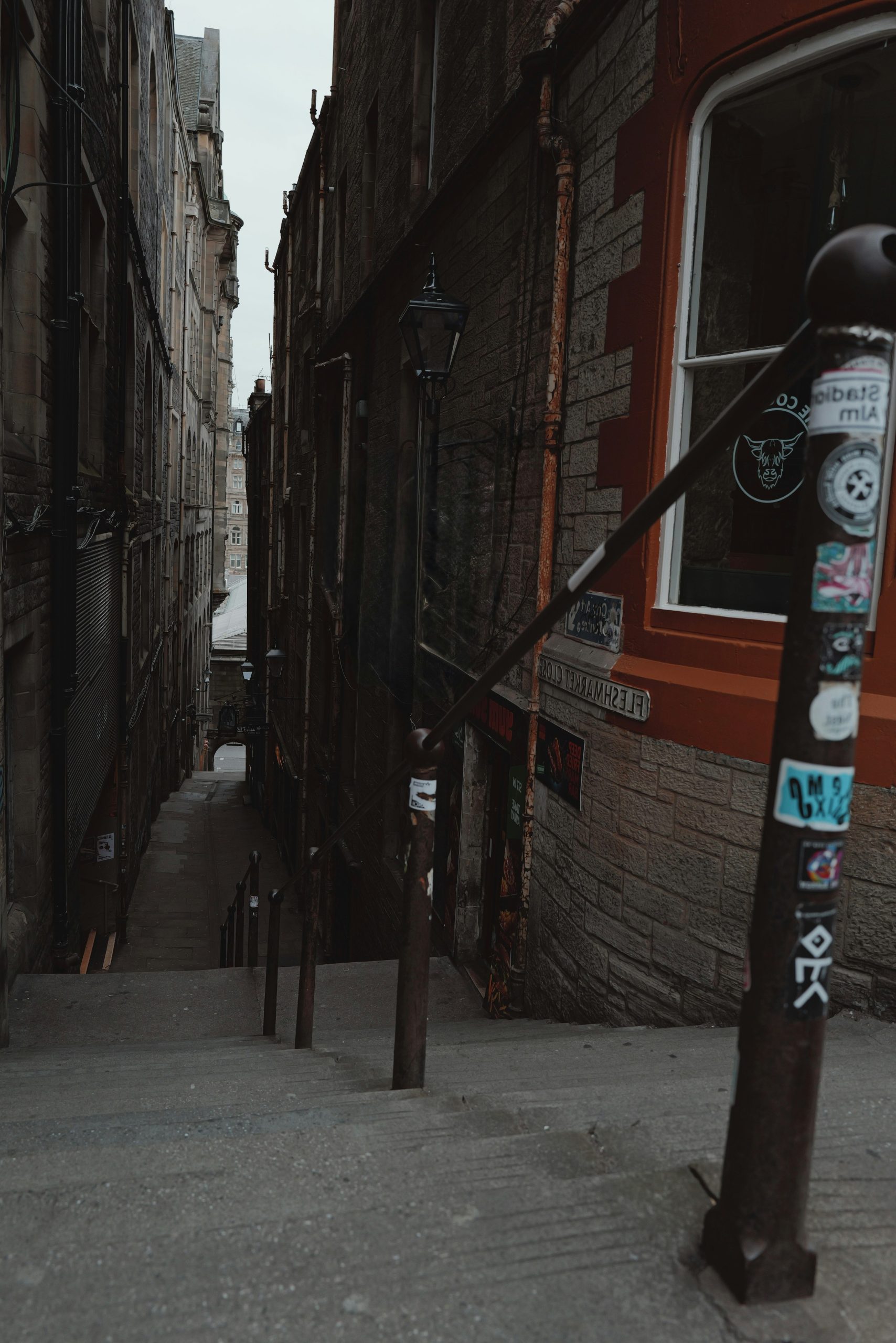 A narrow, dark alleyway with stairs between old buildings.