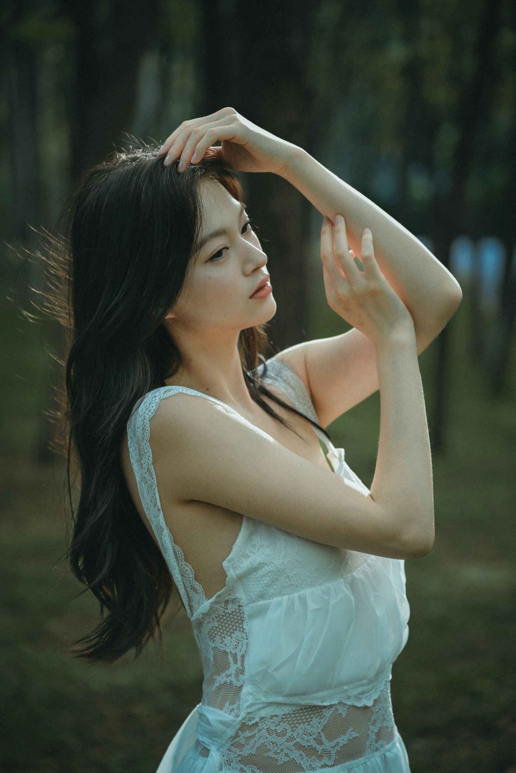 A young woman in a white dress in a forest.