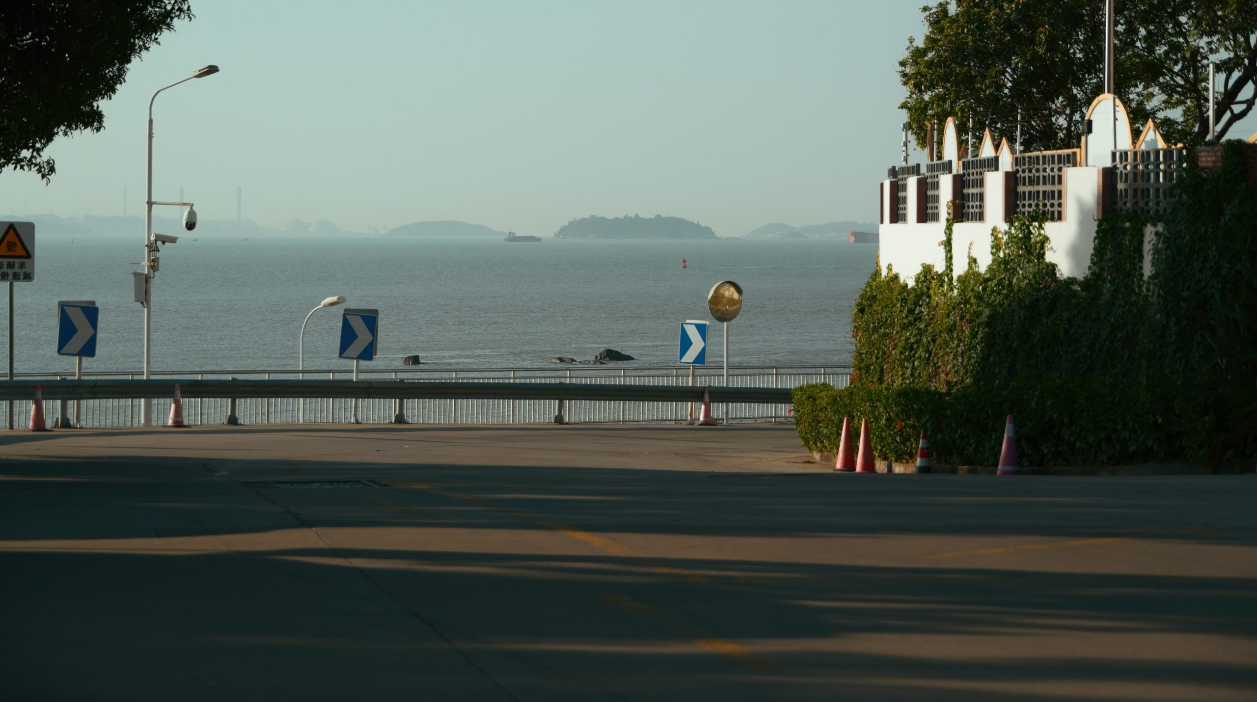 Empty coastal road overlooking the ocean and distant land.