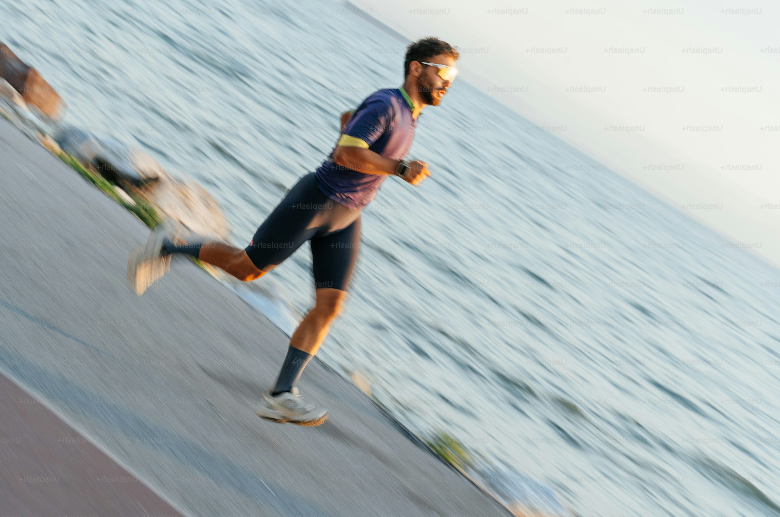 Man running along the water at sunset